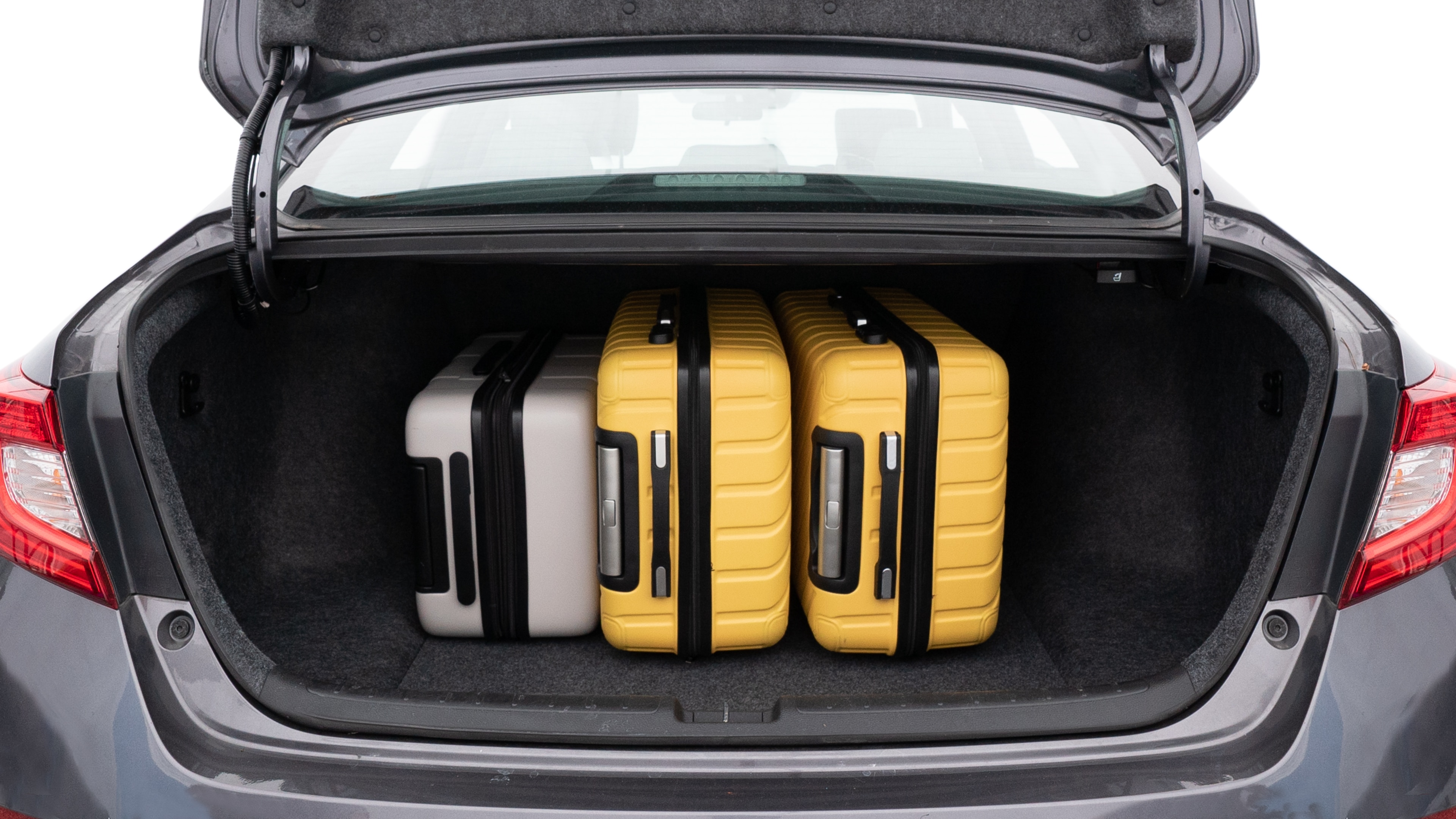 The trunk lid is open, showing full view of the trunk space. One large, two medium, and one small suitcases are placed inside.