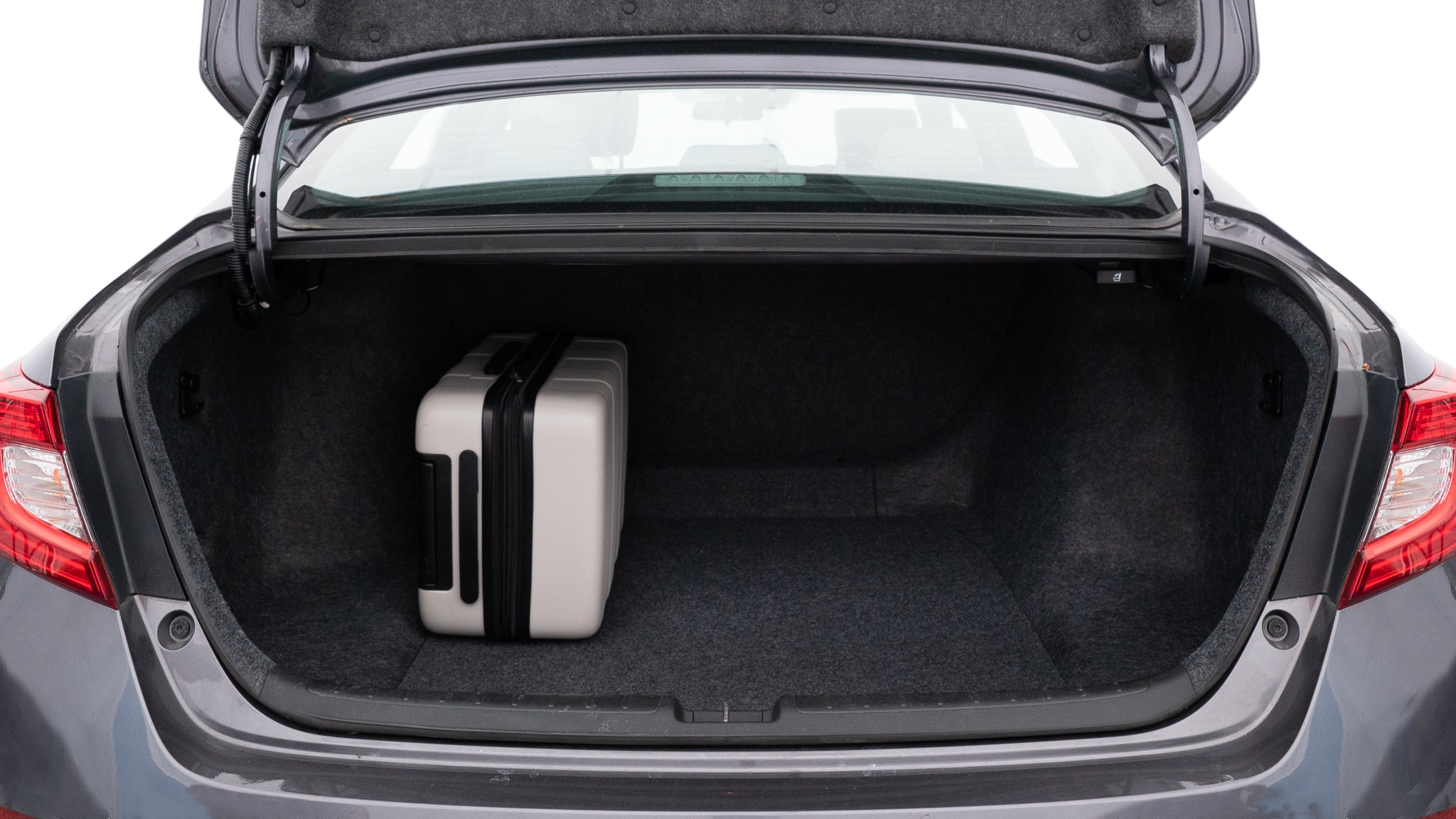The trunk lid is open, showing full view of the trunk space. One large, two medium, and one small suitcases are placed inside.