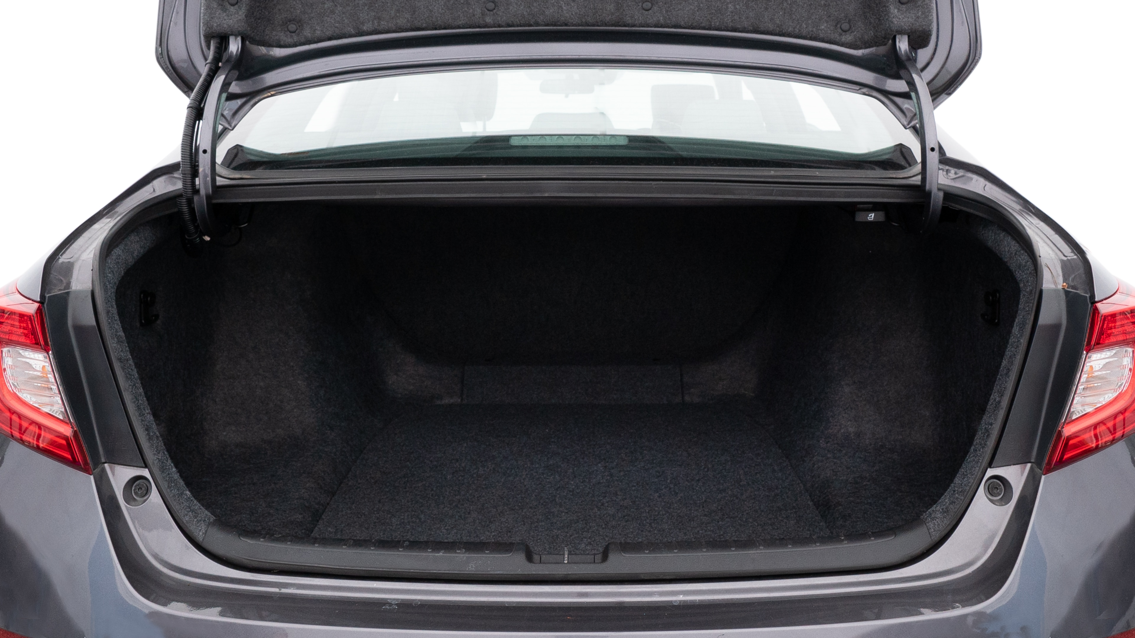 The trunk lid is open, showing full view of the trunk space. One large, two medium, and one small suitcases are placed inside.
