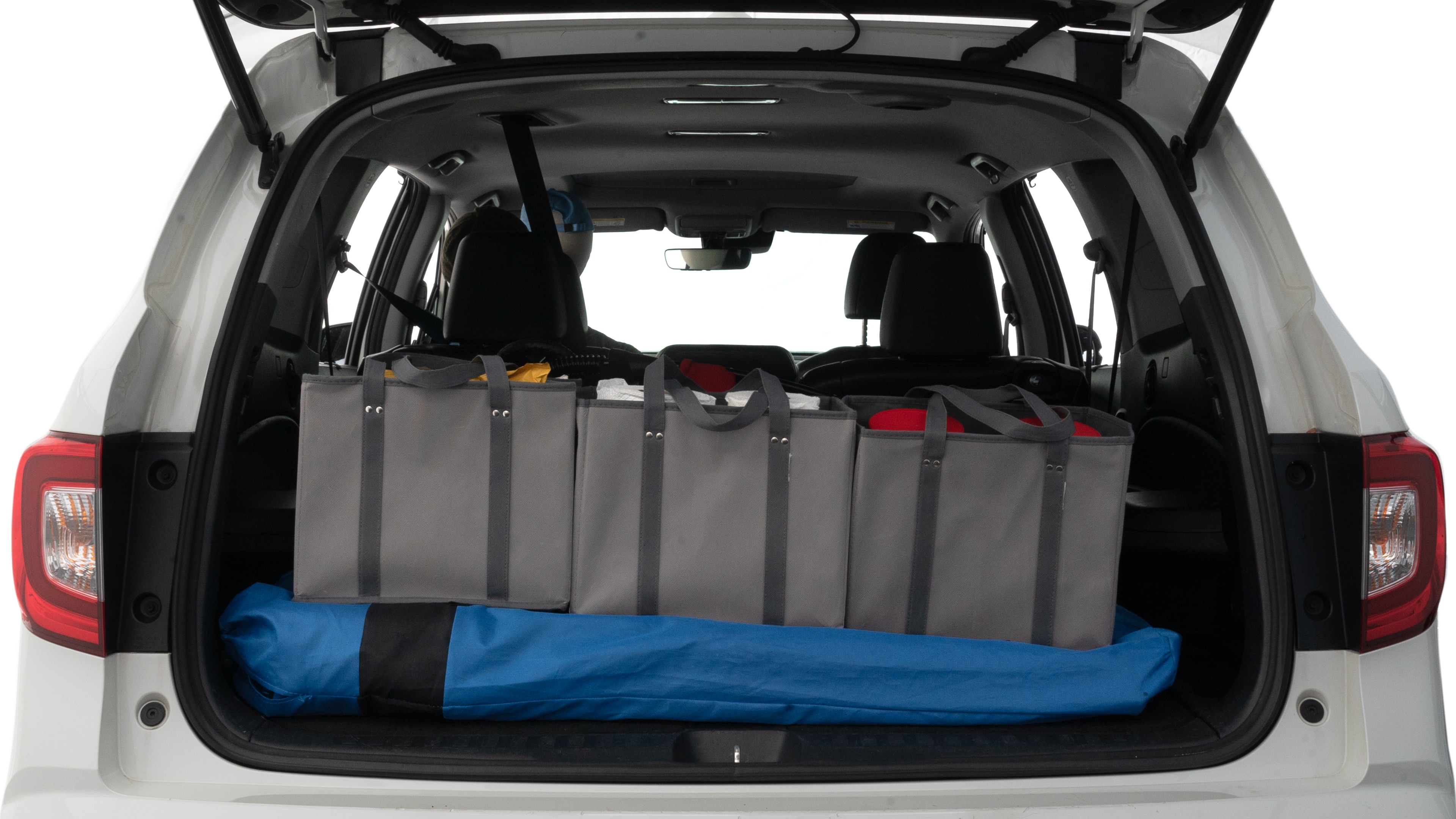 The trunk lid is open showing full view of the trunk. A baby stroller, three grocery carriers and two camping chairs in the carrying bag are placed inside.