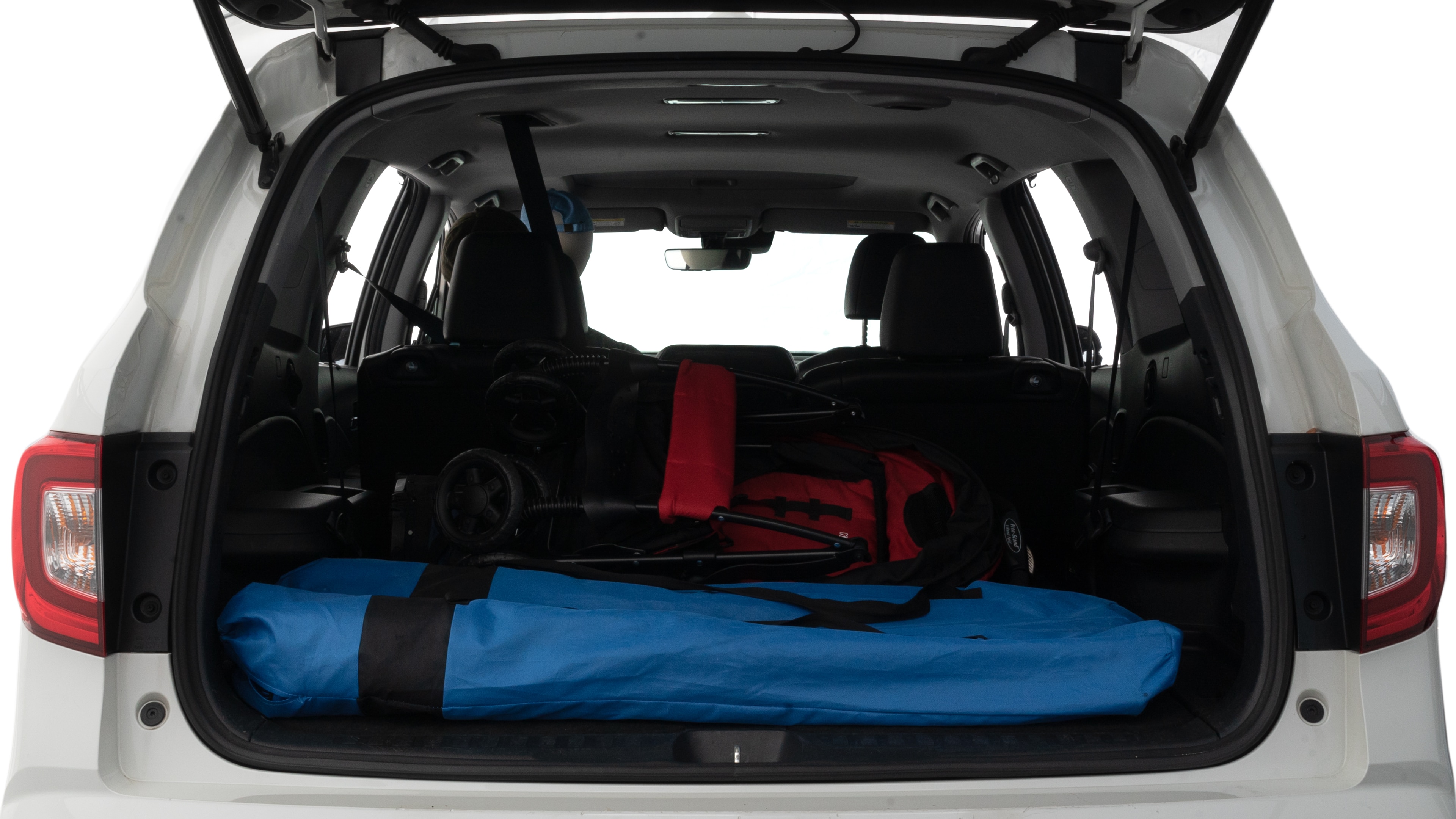 The trunk lid is open showing full view of the trunk. A baby stroller, three grocery carriers and two camping chairs in the carrying bag are placed inside.