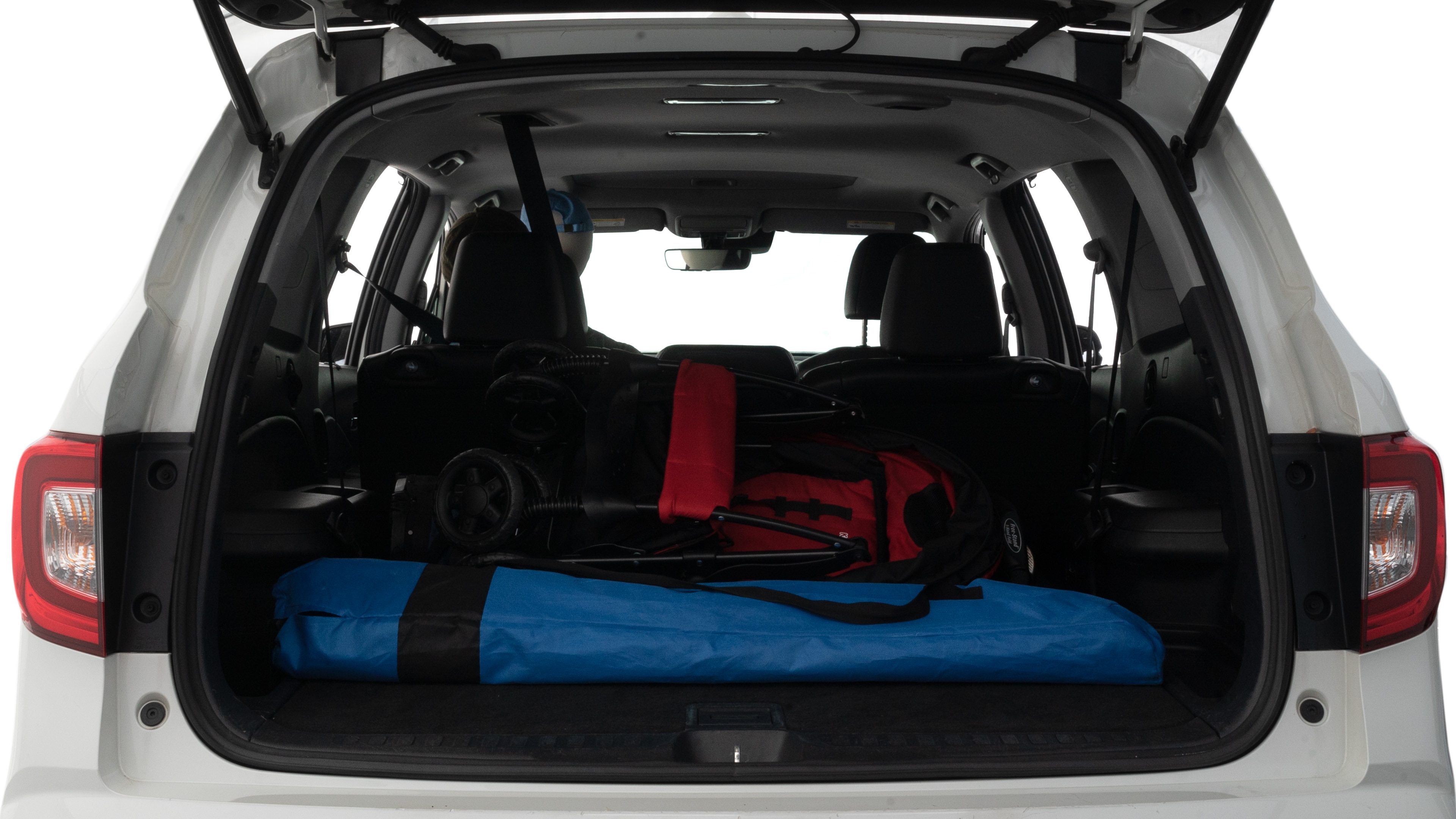 The trunk lid is open showing full view of the trunk. A baby stroller, three grocery carriers and two camping chairs in the carrying bag are placed inside.