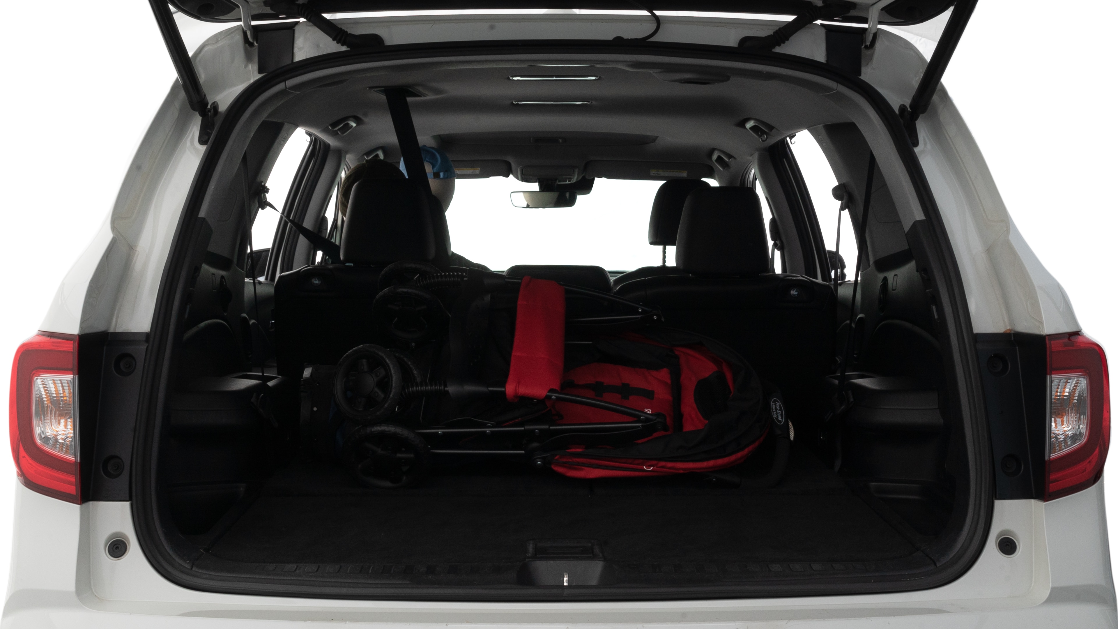 The trunk lid is open showing full view of the trunk. A baby stroller, three grocery carriers and two camping chairs in the carrying bag are placed inside.