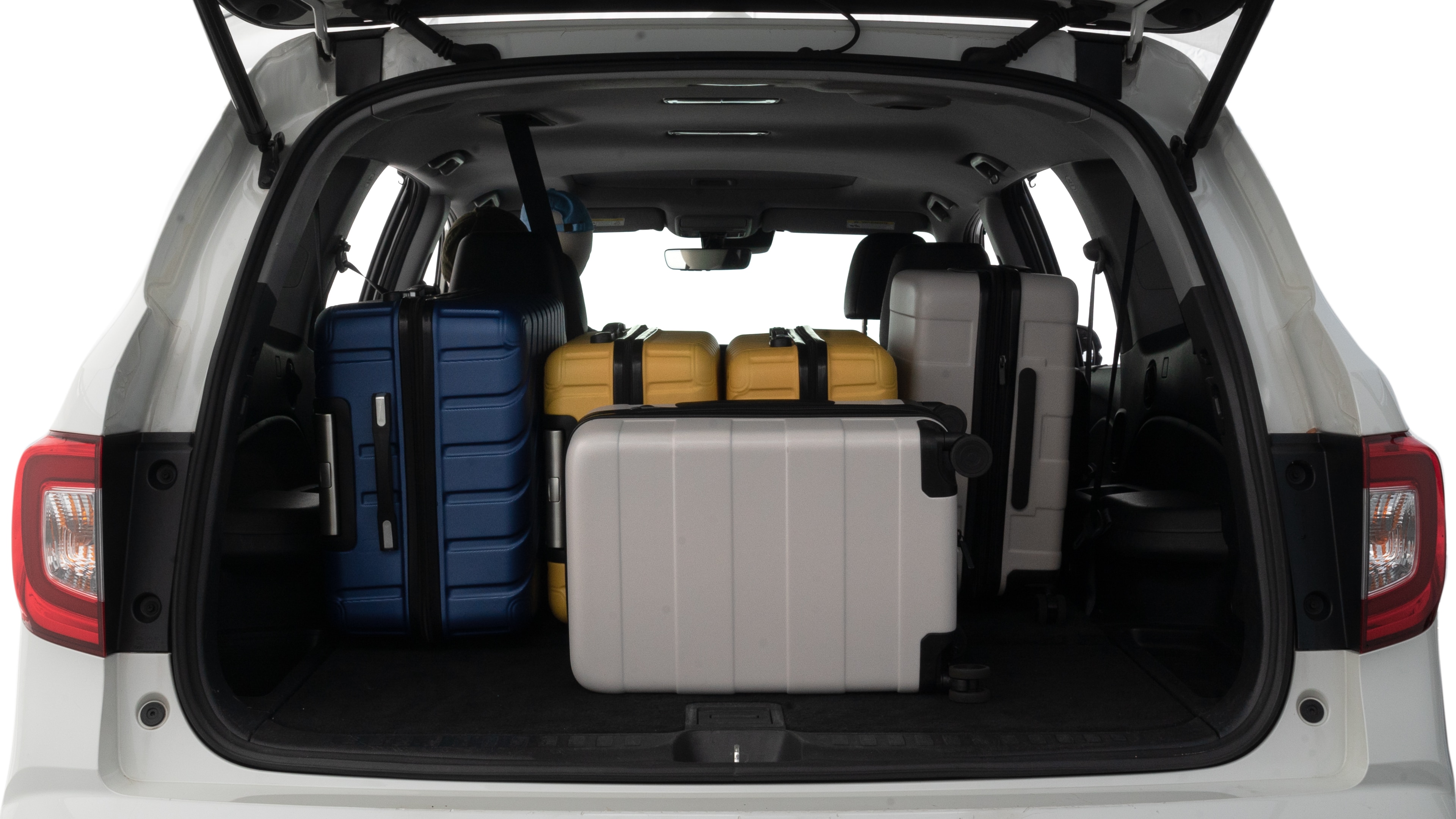 The trunk lid is open, showing full view of the trunk space. Two large and one small suitcases are placed inside.