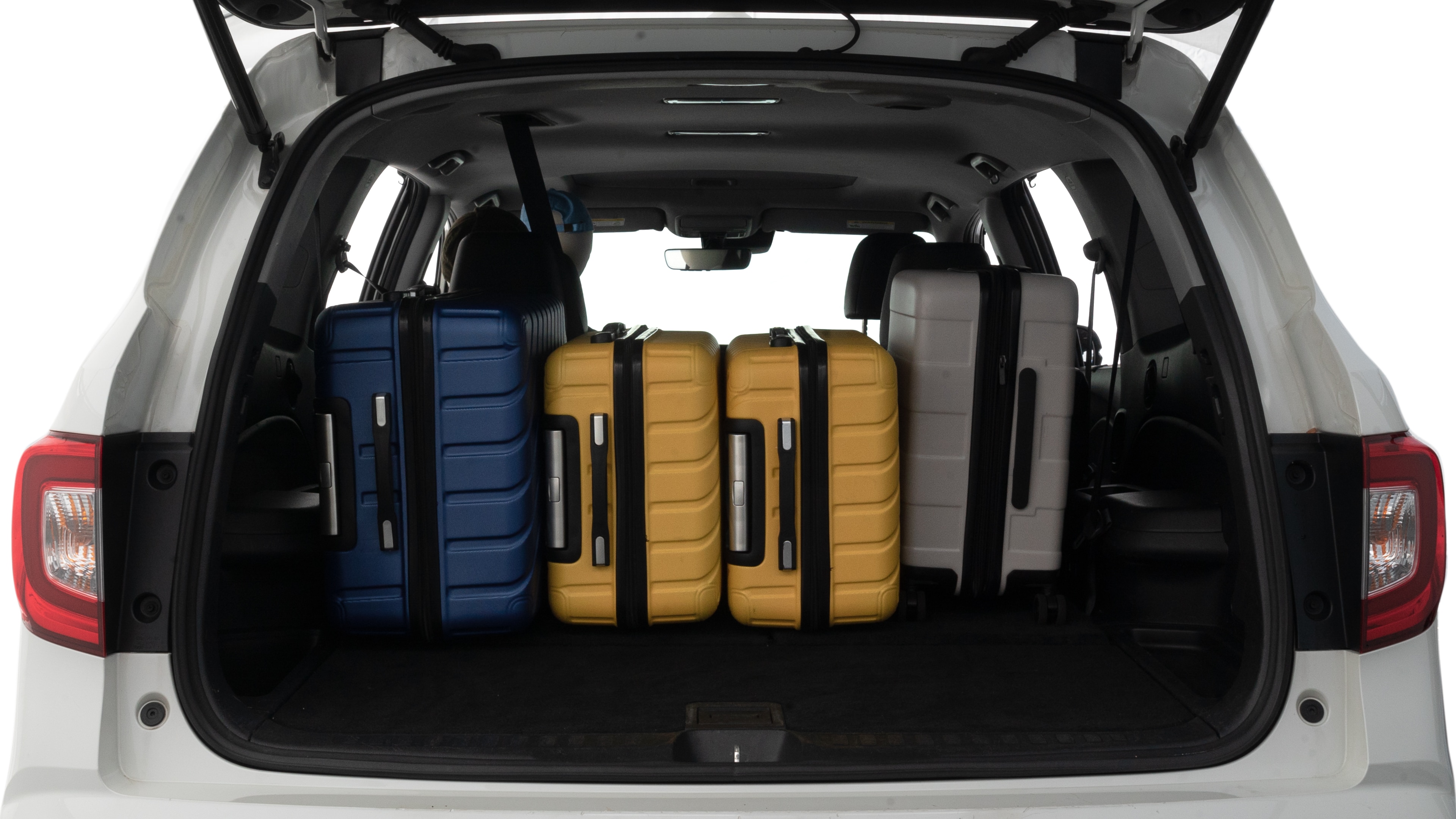 The trunk lid is open, showing full view of the trunk space. Two large and one small suitcases are placed inside.