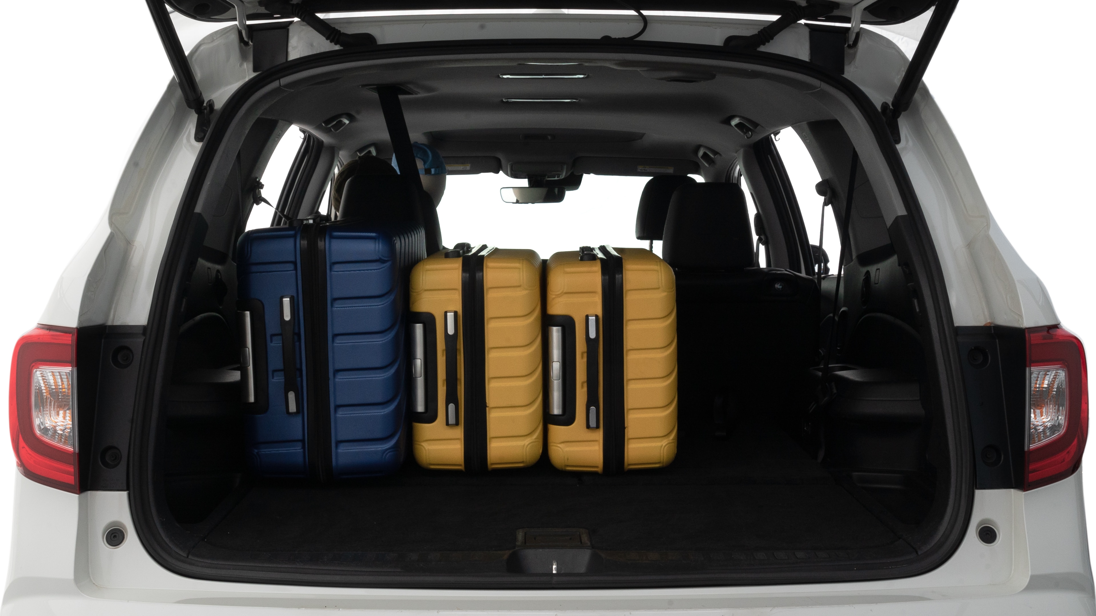 The trunk lid is open, showing full view of the trunk space. Two large and one small suitcases are placed inside.