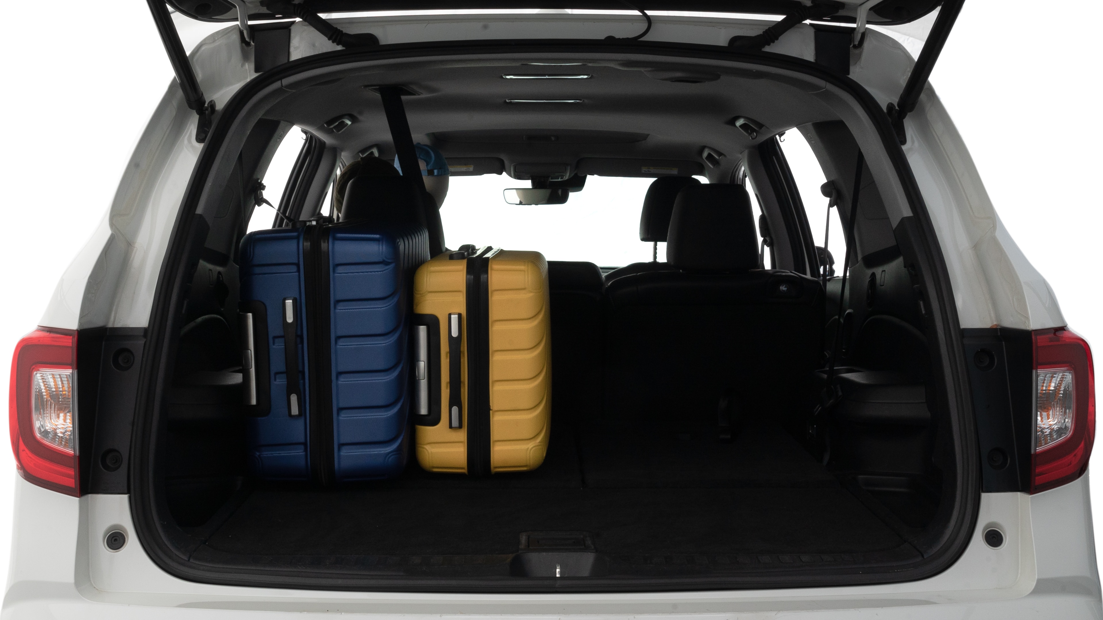 The trunk lid is open, showing full view of the trunk space. Two large and one small suitcases are placed inside.