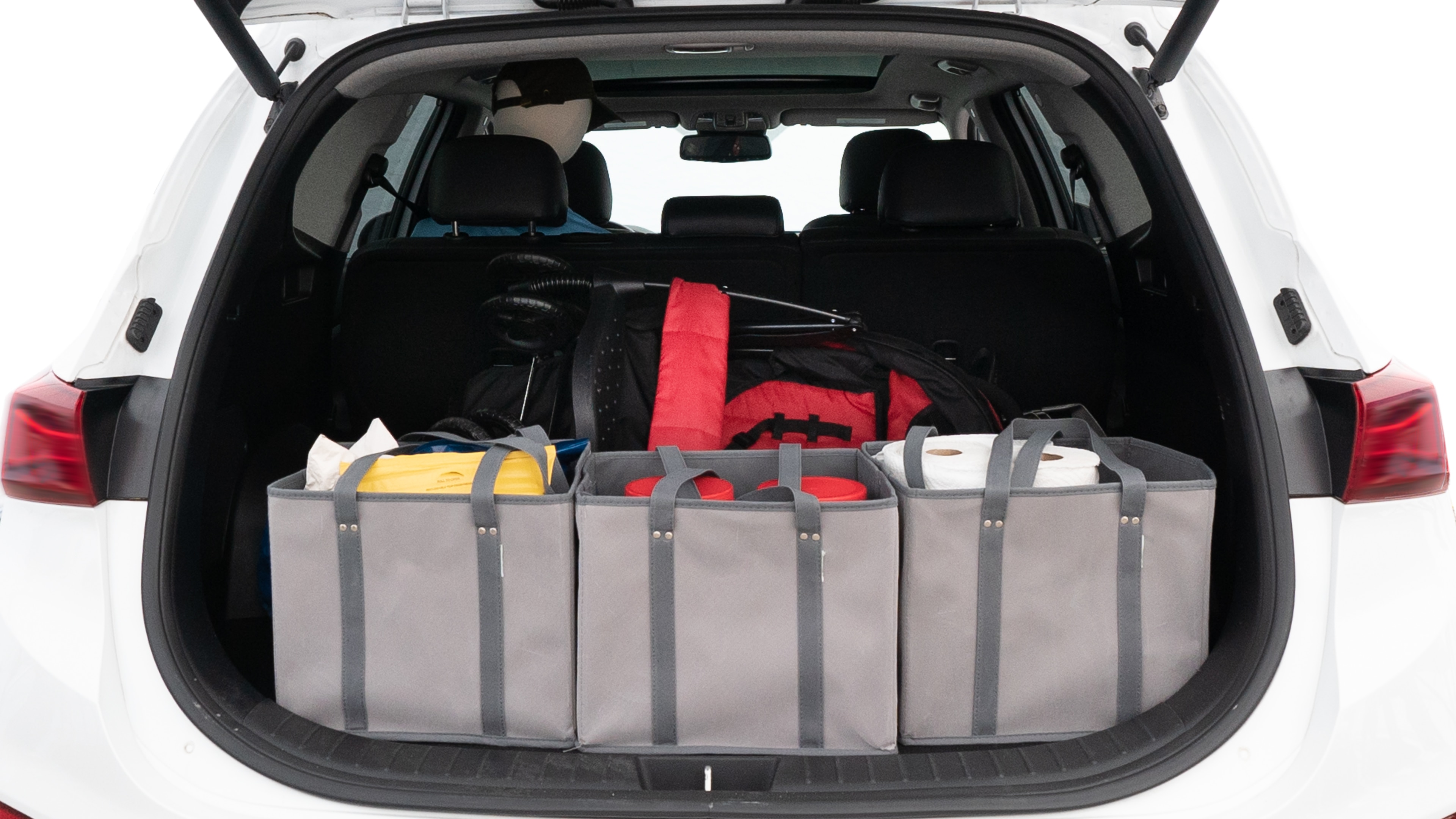 The trunk lid is open showing full view of the trunk. A baby stroller, three grocery carriers, two camping chairs in the carrying bag, and a set of golf clubs are placed inside.