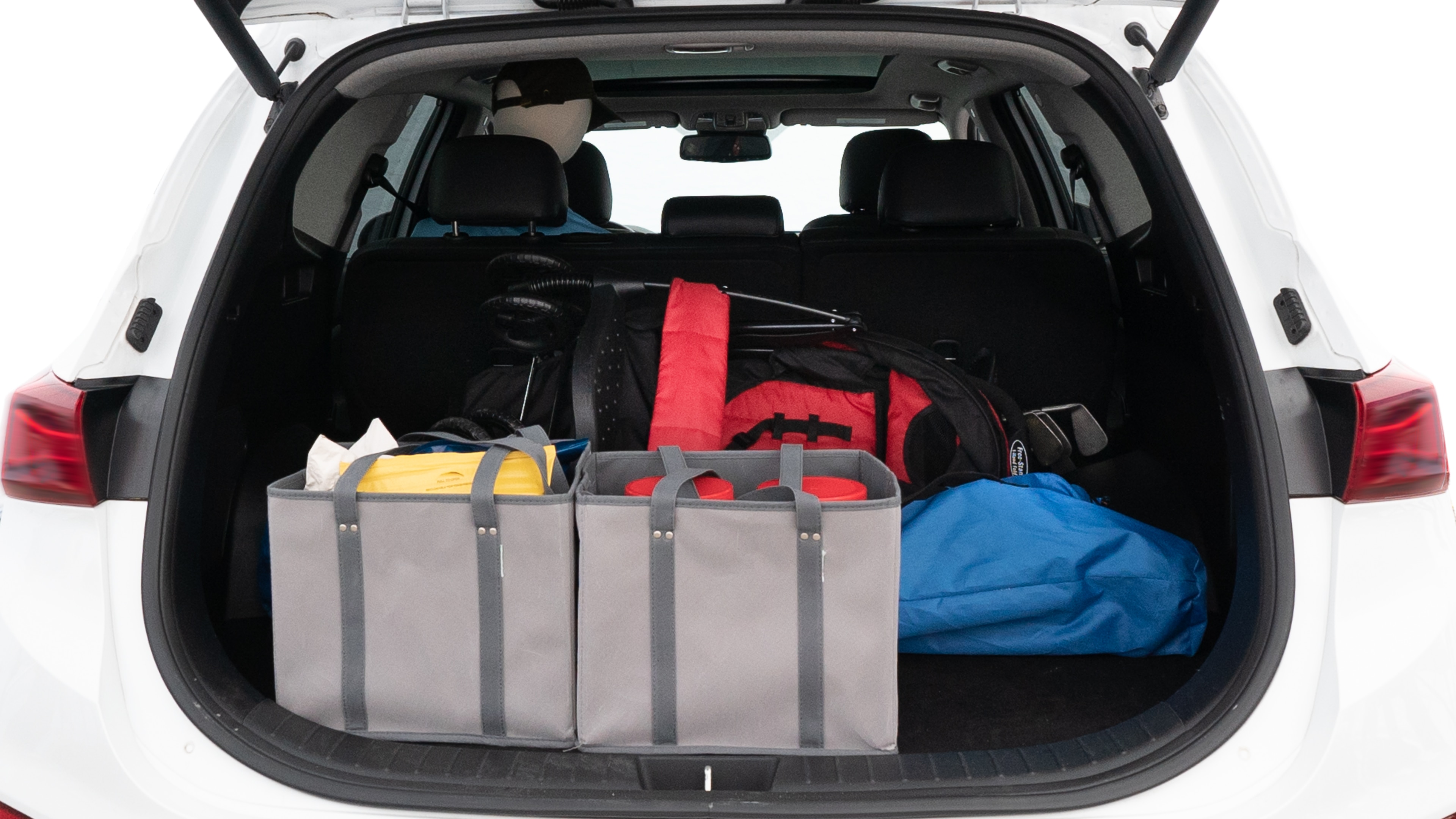 The trunk lid is open showing full view of the trunk. A baby stroller, three grocery carriers, two camping chairs in the carrying bag, and a set of golf clubs are placed inside.