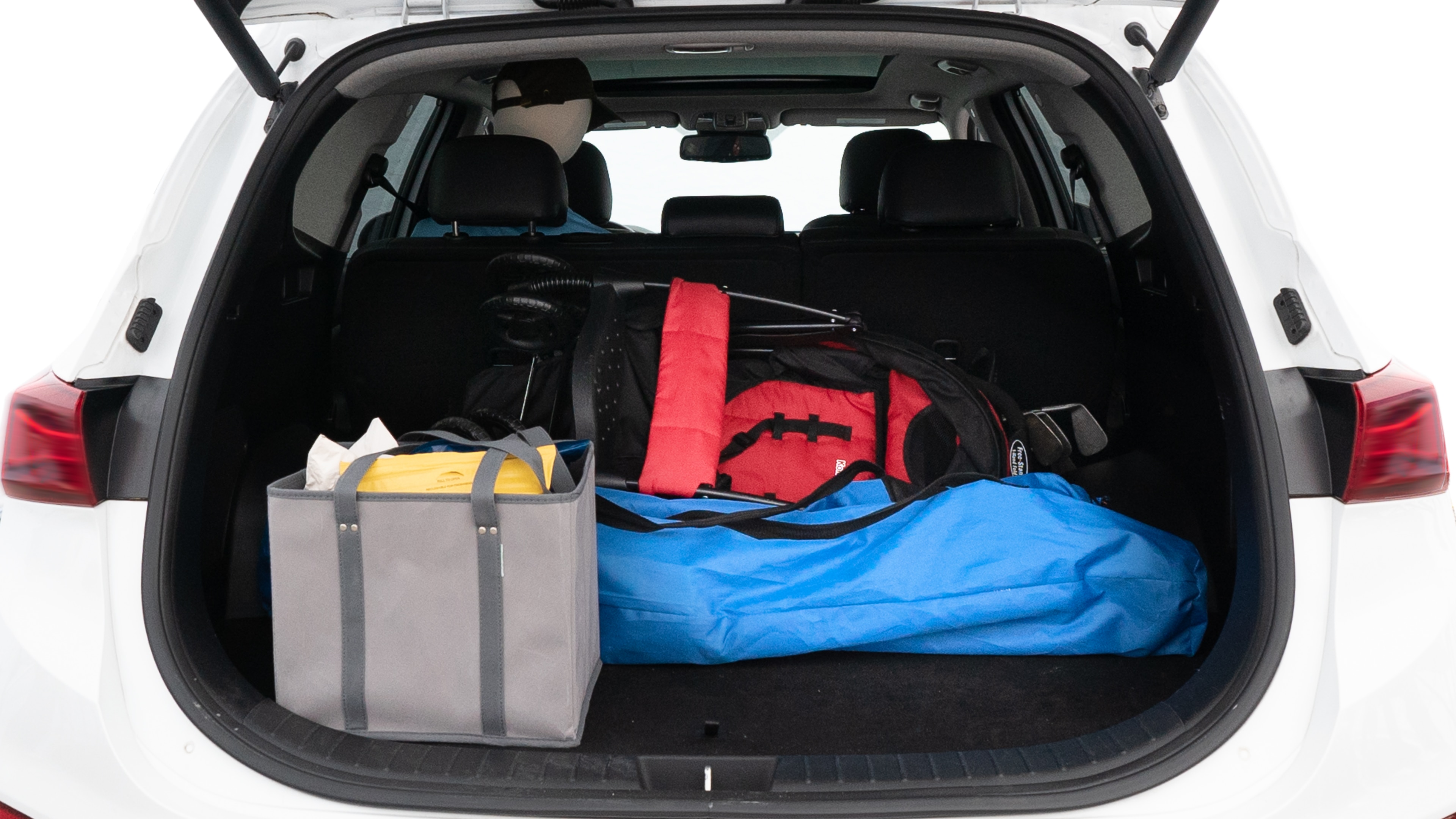 The trunk lid is open showing full view of the trunk. A baby stroller, three grocery carriers, two camping chairs in the carrying bag, and a set of golf clubs are placed inside.