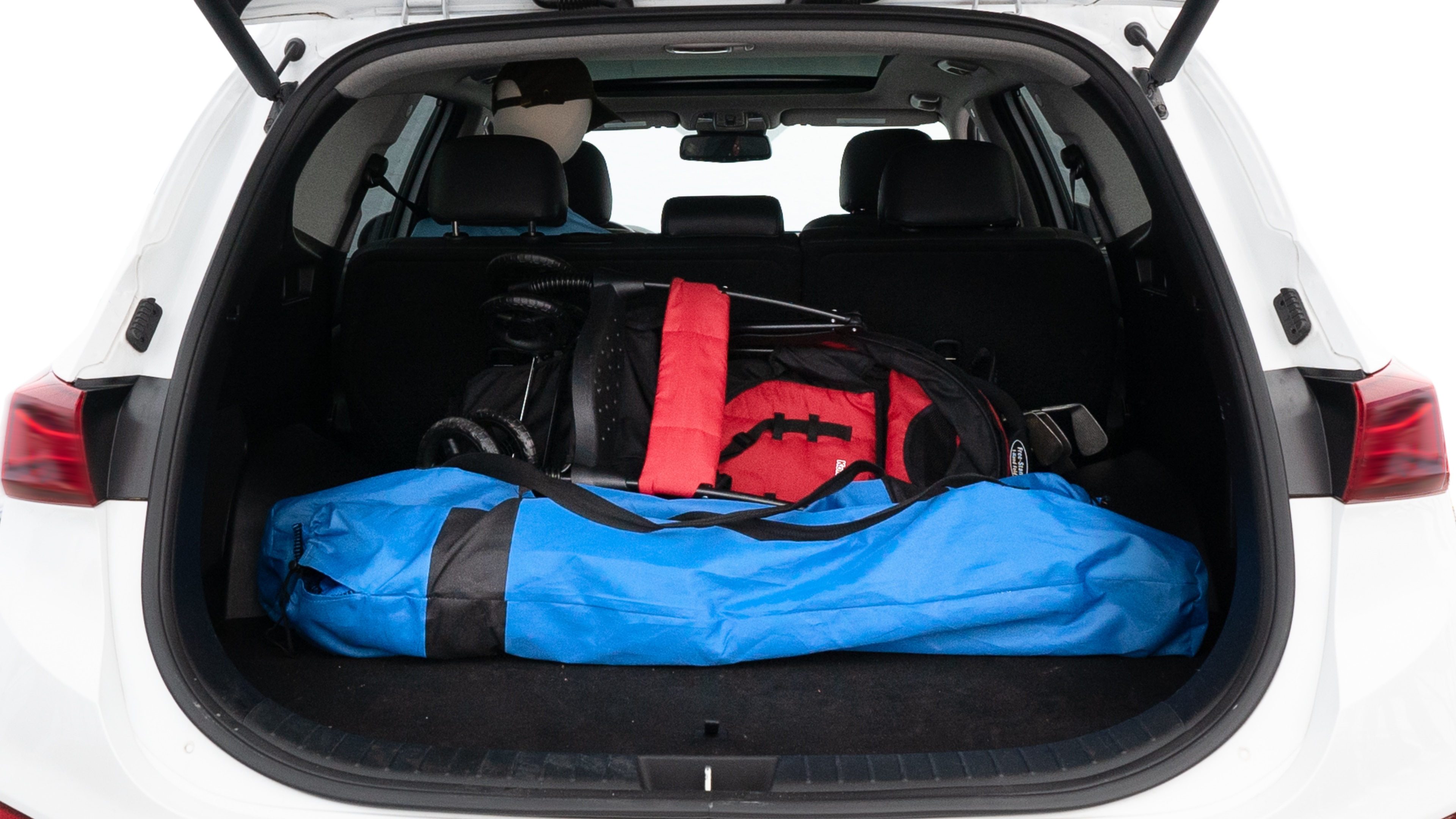 The trunk lid is open showing full view of the trunk. A baby stroller, three grocery carriers, two camping chairs in the carrying bag, and a set of golf clubs are placed inside.