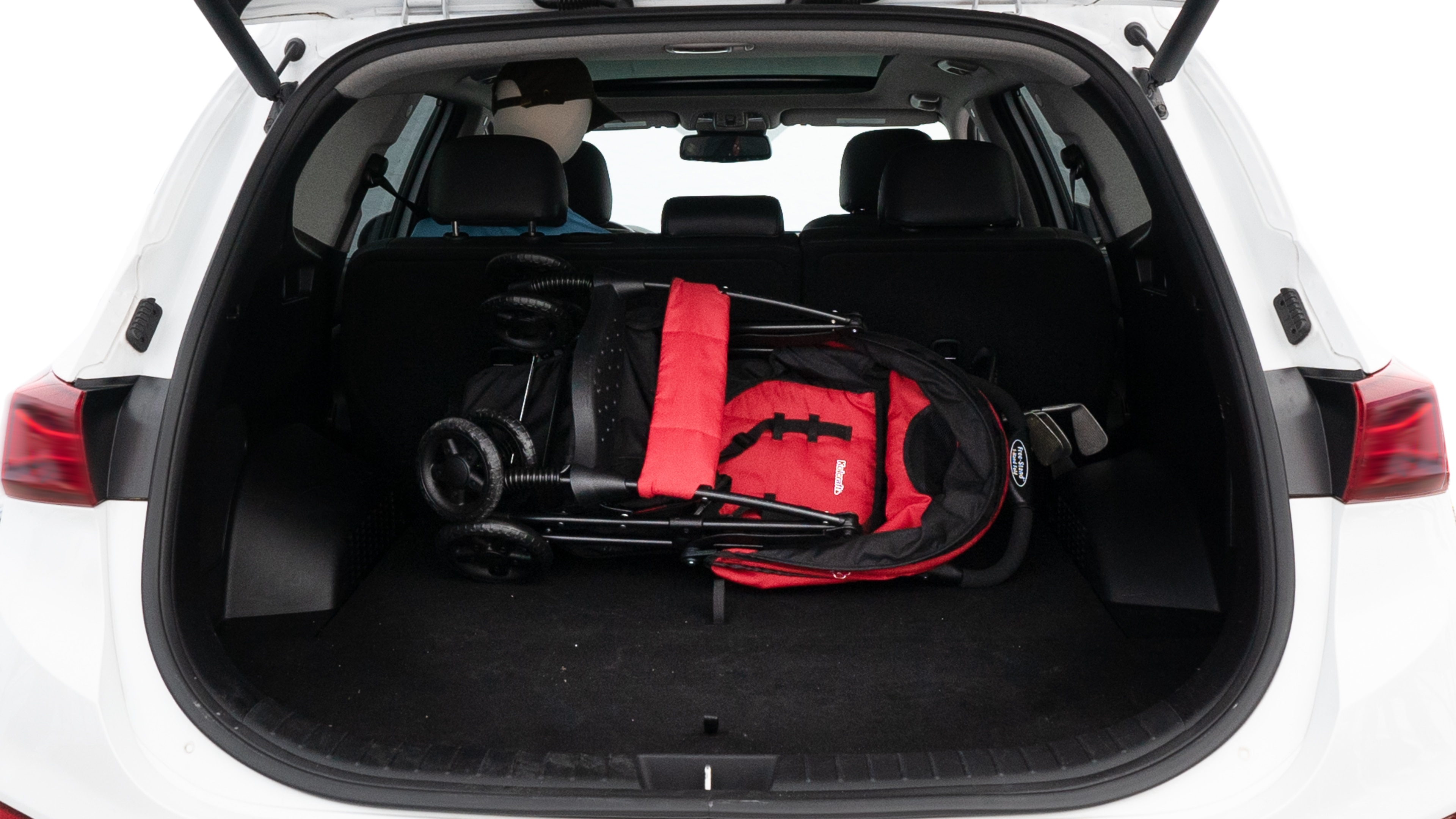The trunk lid is open showing full view of the trunk. A baby stroller, three grocery carriers, two camping chairs in the carrying bag, and a set of golf clubs are placed inside.