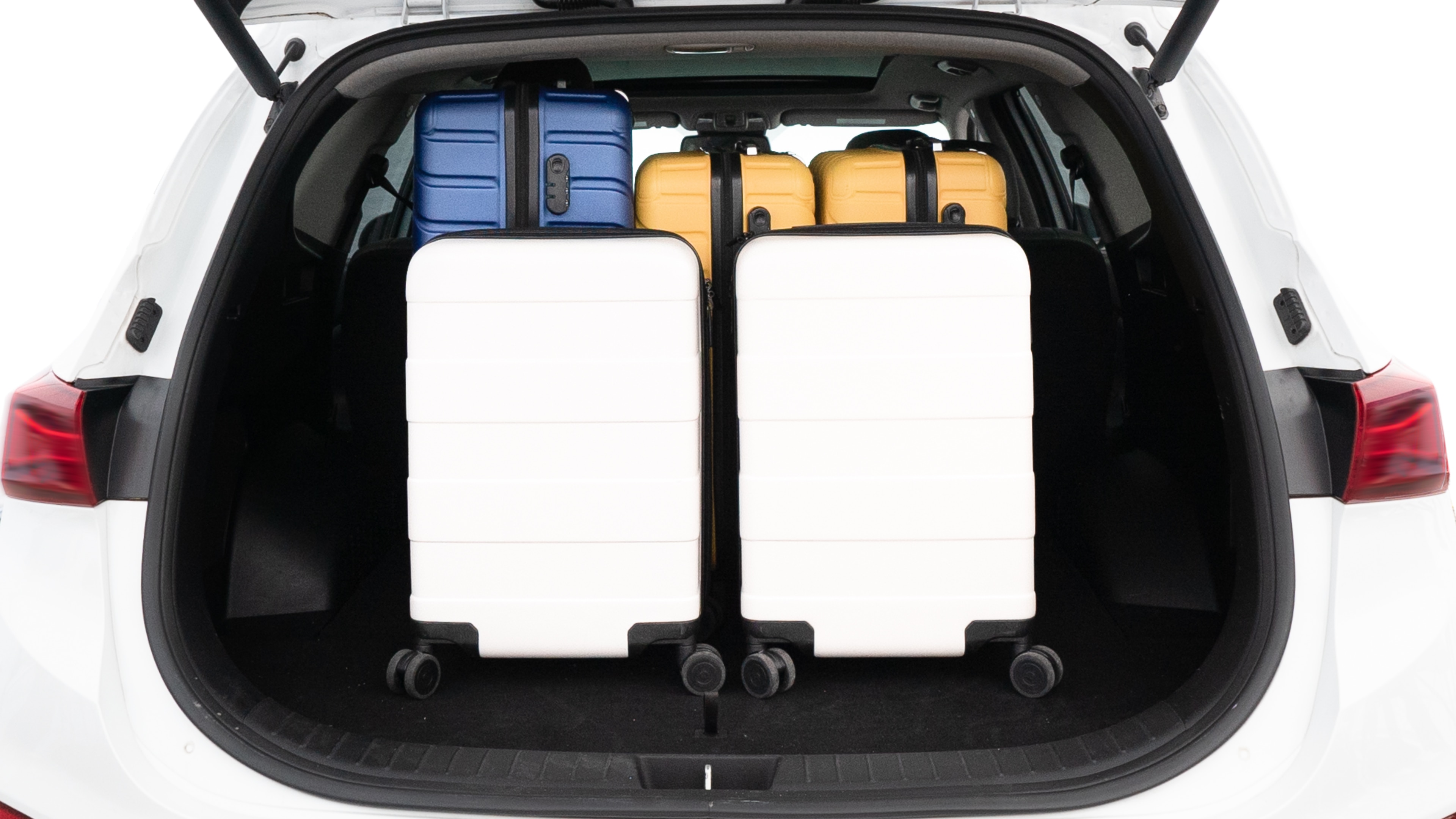 The trunk lid is open, showing full view of the trunk space. One large, two medium, and two small suitcases are placed inside.