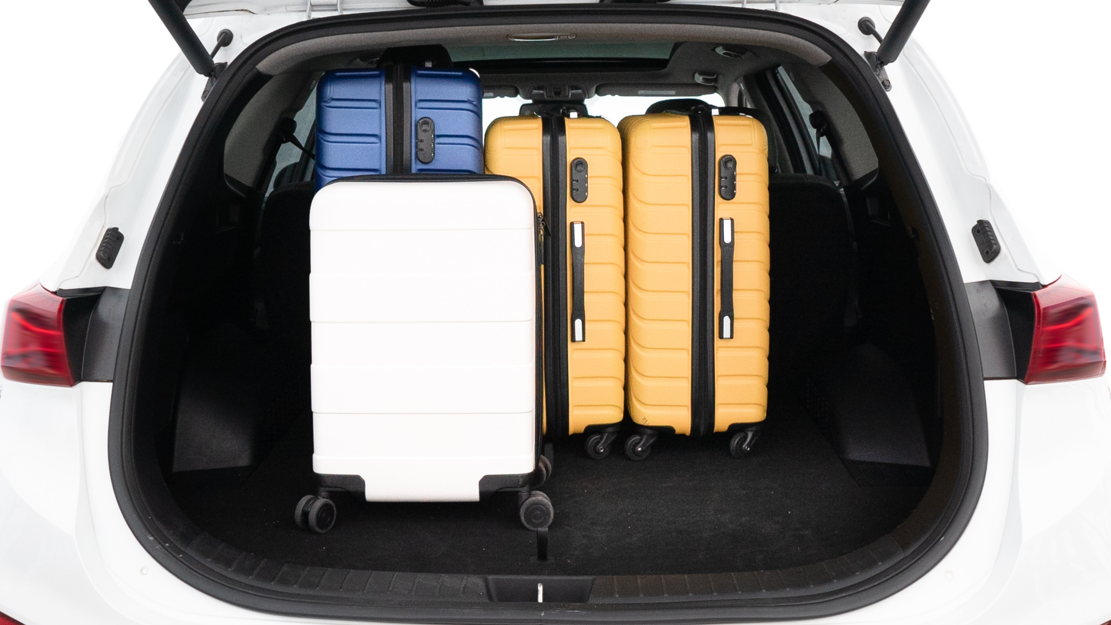 The trunk lid is open, showing full view of the trunk space. One large, two medium, and two small suitcases are placed inside.