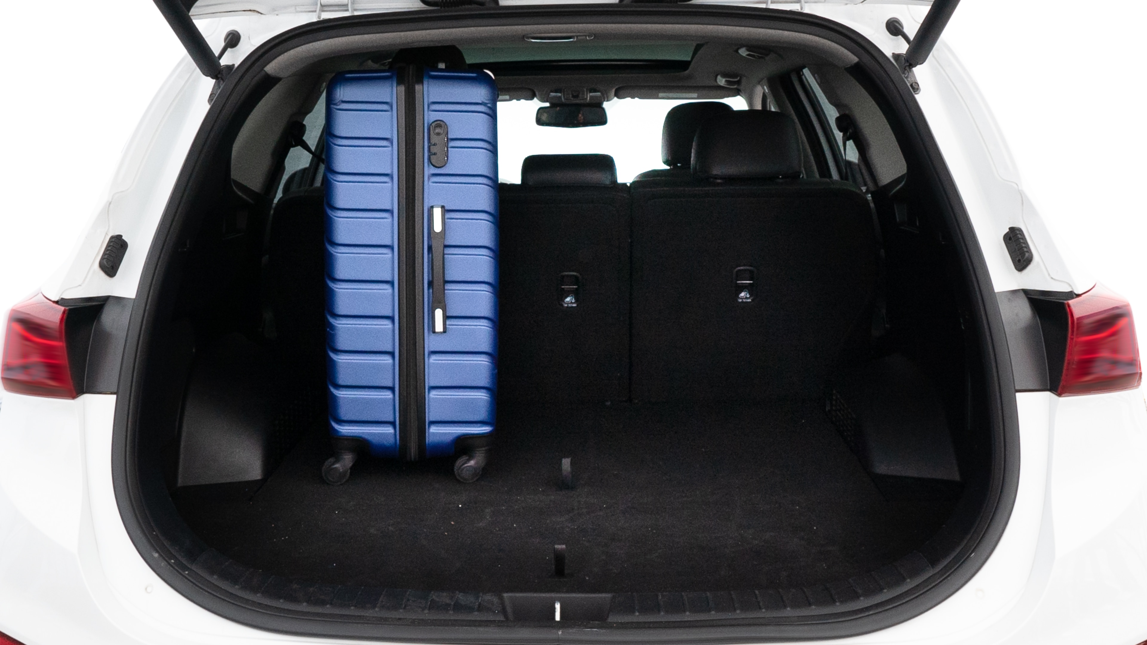 The trunk lid is open, showing full view of the trunk space. One large, two medium, and two small suitcases are placed inside.