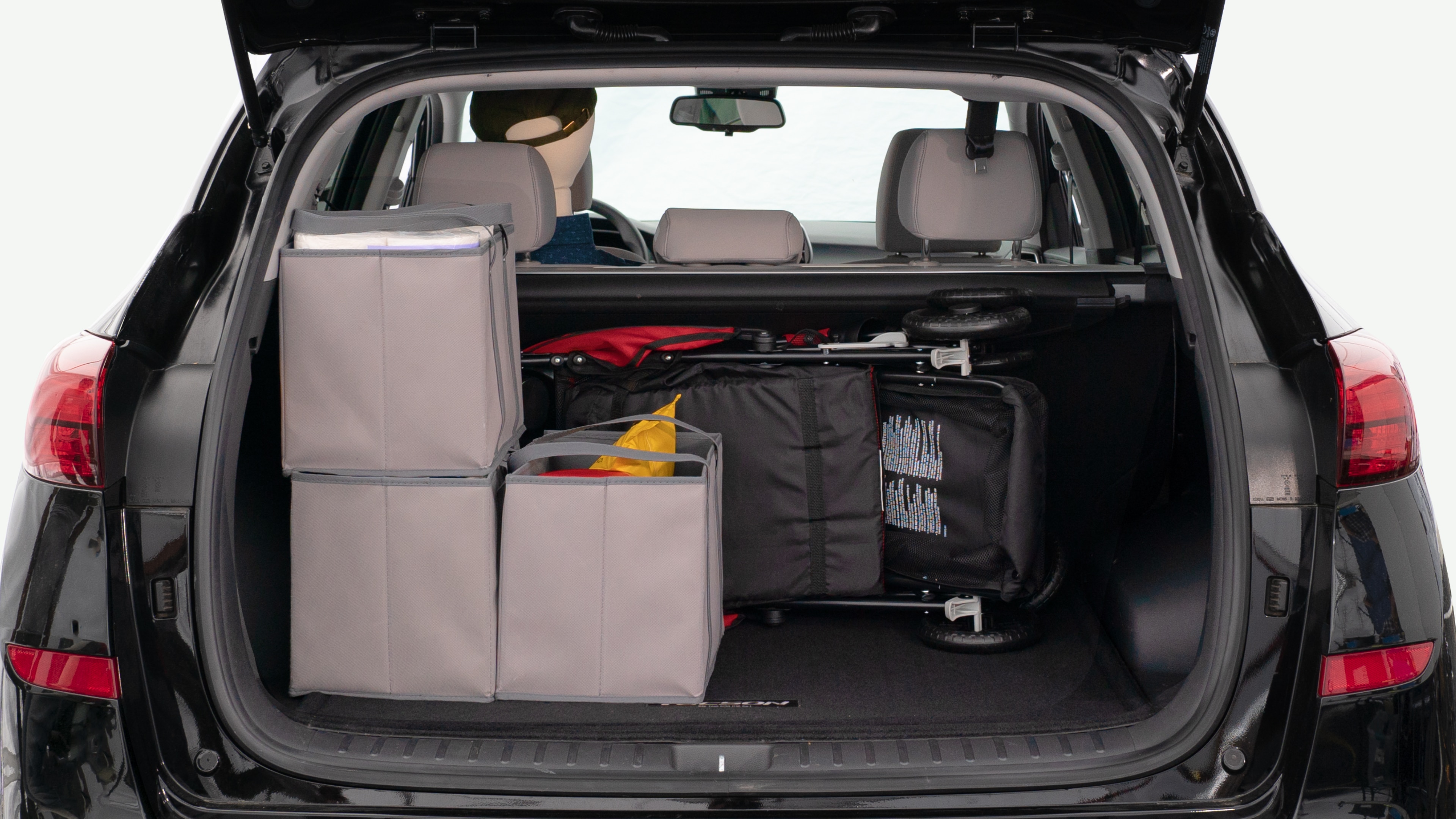 The trunk lid is open showing full view of the trunk. A baby stroller, three grocery carriers, and a set of golf clubs are placed inside.