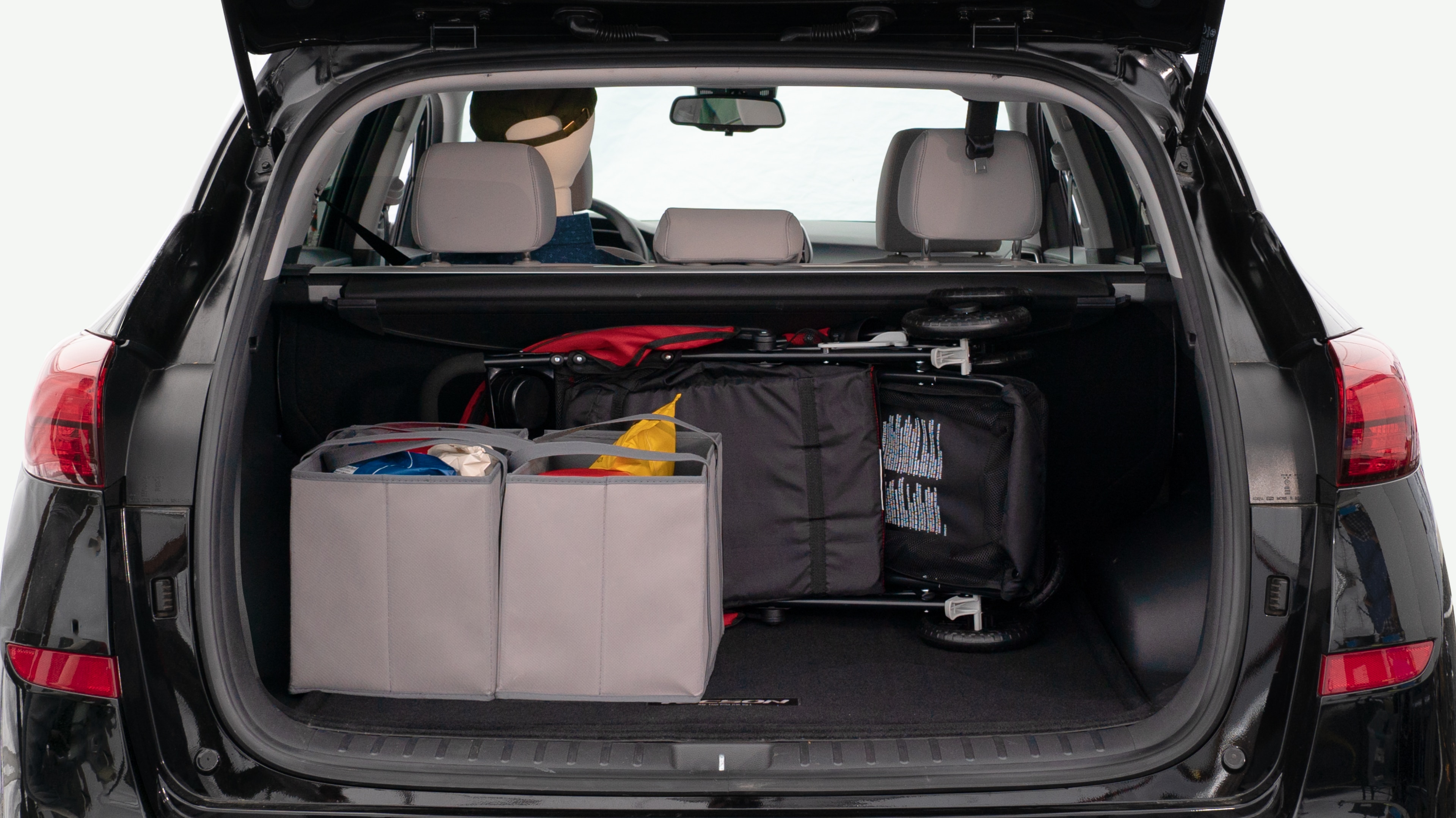 The trunk lid is open showing full view of the trunk. A baby stroller, three grocery carriers, and a set of golf clubs are placed inside.