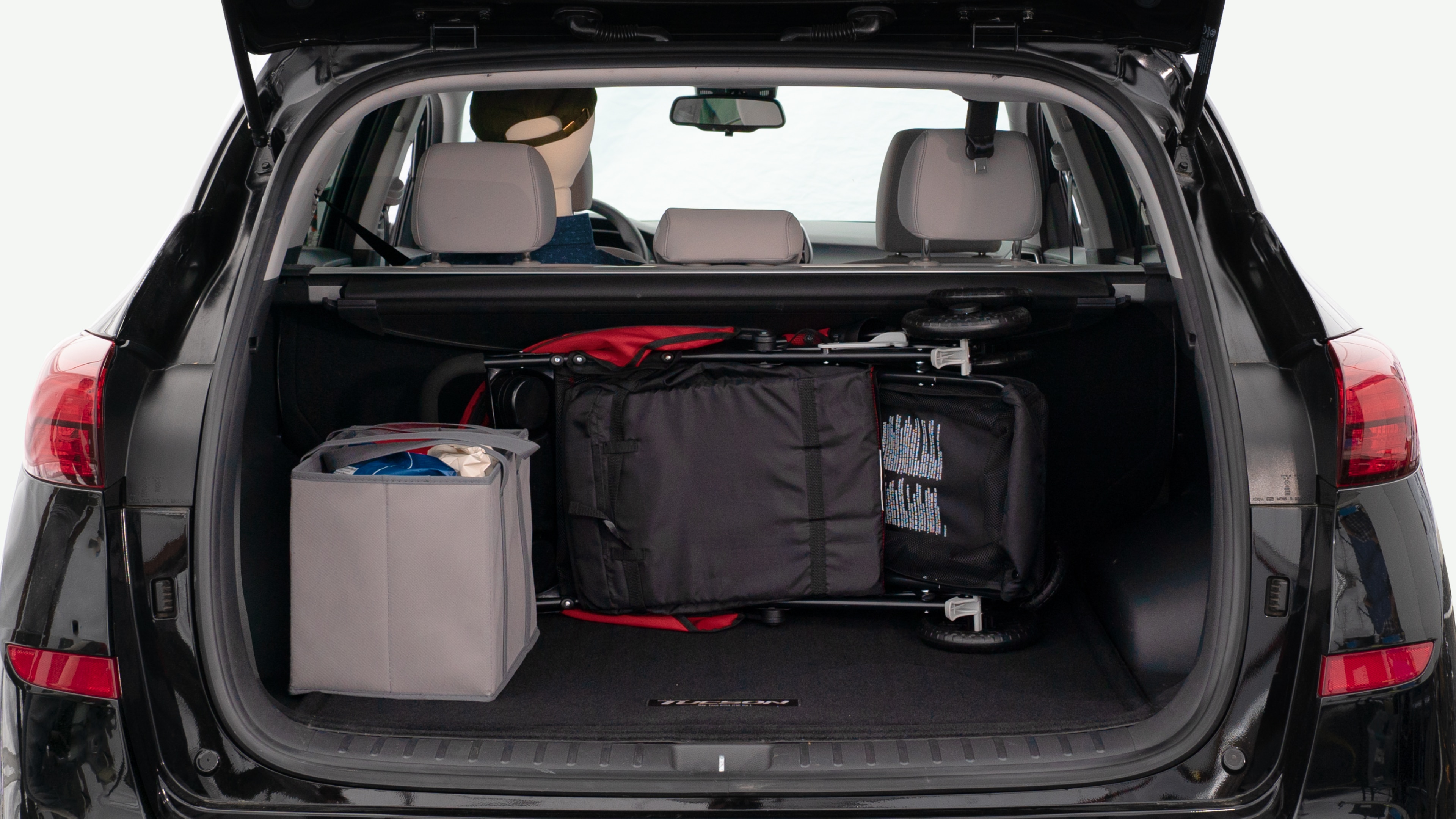 The trunk lid is open showing full view of the trunk. A baby stroller, three grocery carriers, and a set of golf clubs are placed inside.
