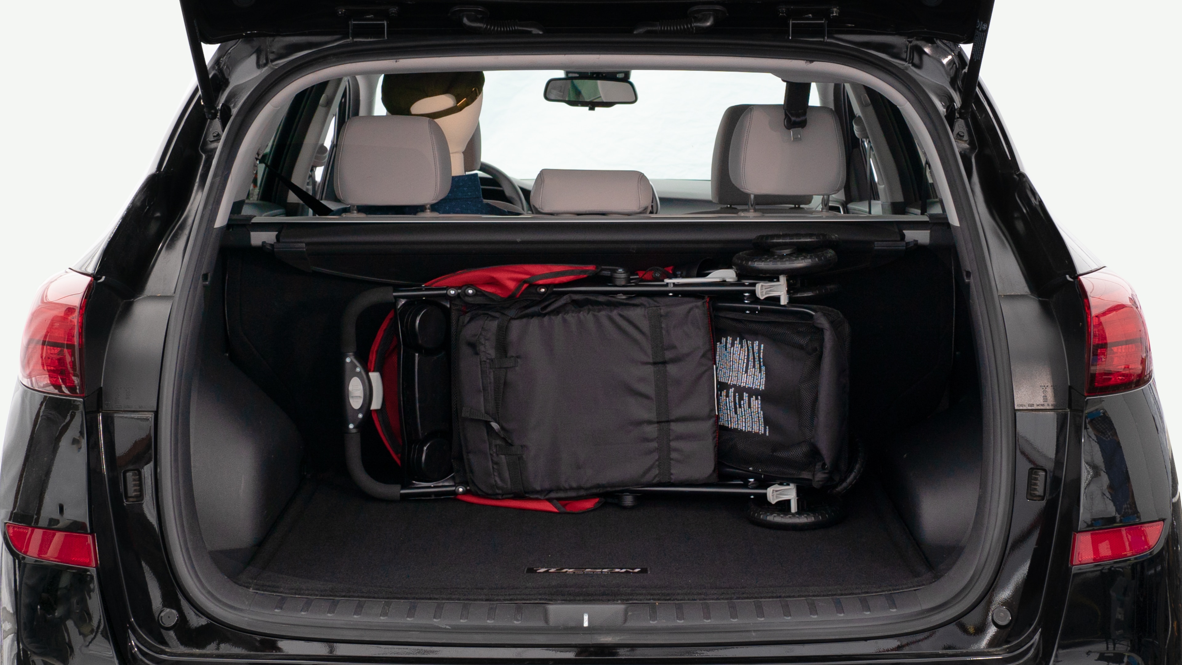 The trunk lid is open showing full view of the trunk. A baby stroller, three grocery carriers, and a set of golf clubs are placed inside.