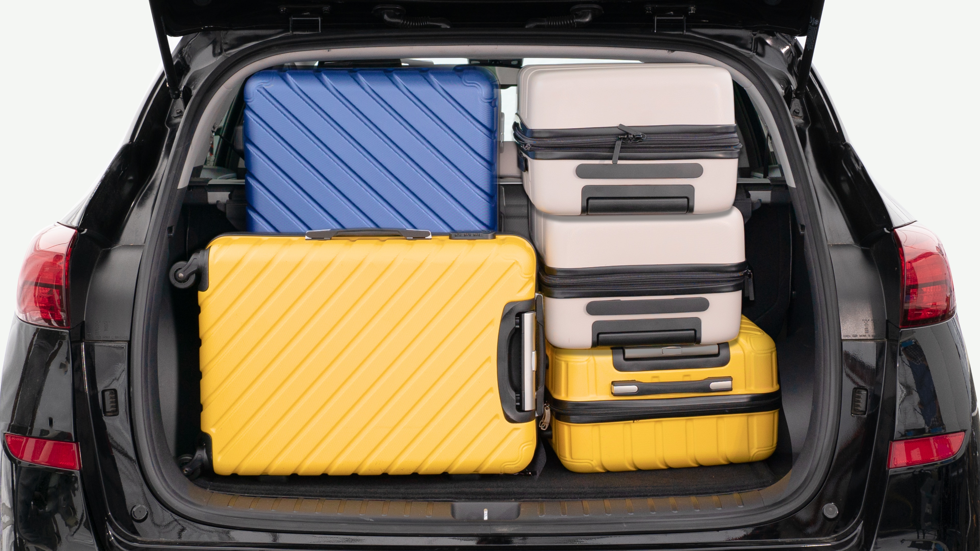 The trunk lid is open, showing a full view of the trunk space. Three large and two small suitcases are placed inside.