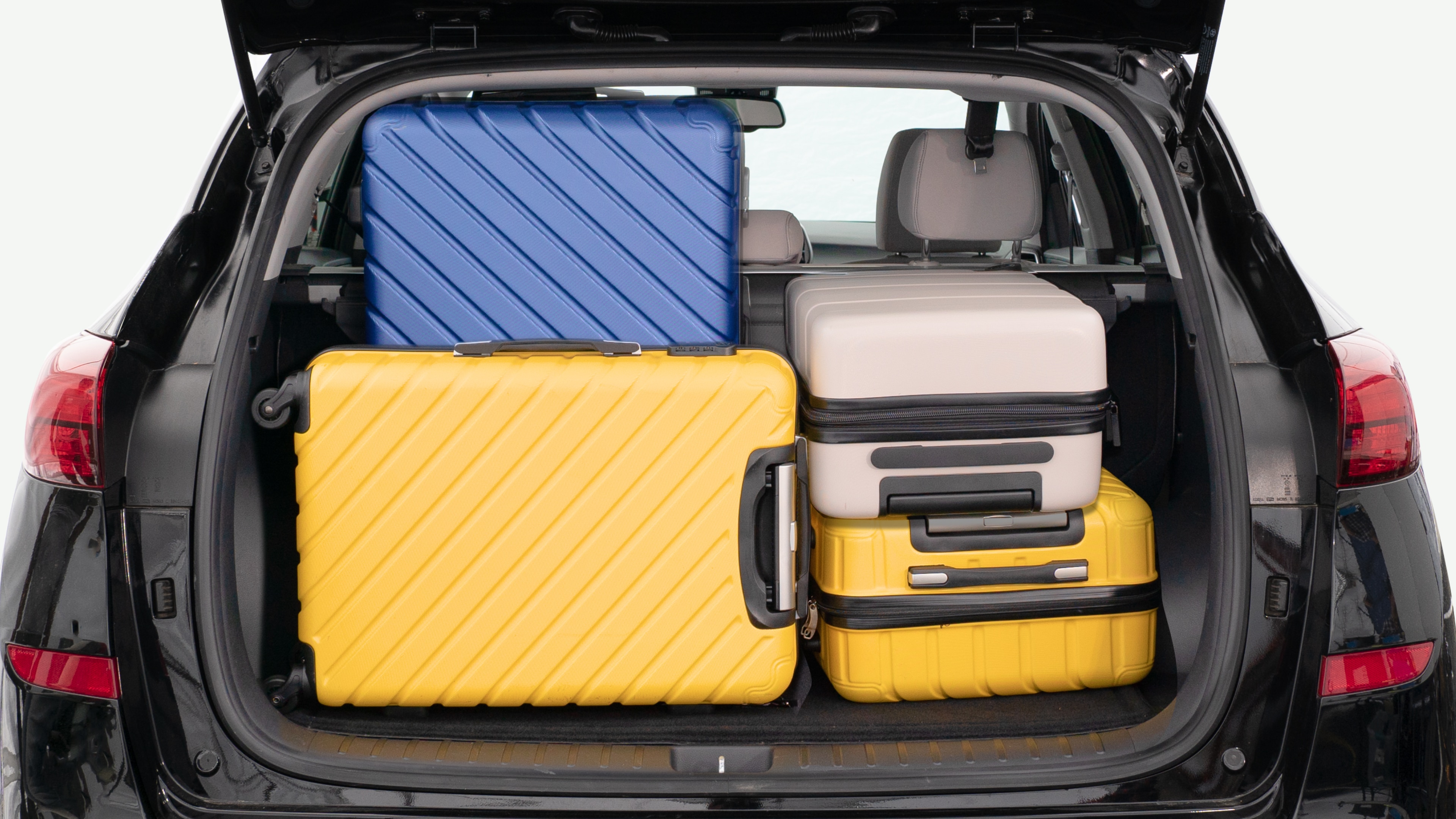 The trunk lid is open, showing a full view of the trunk space. Three large and two small suitcases are placed inside.