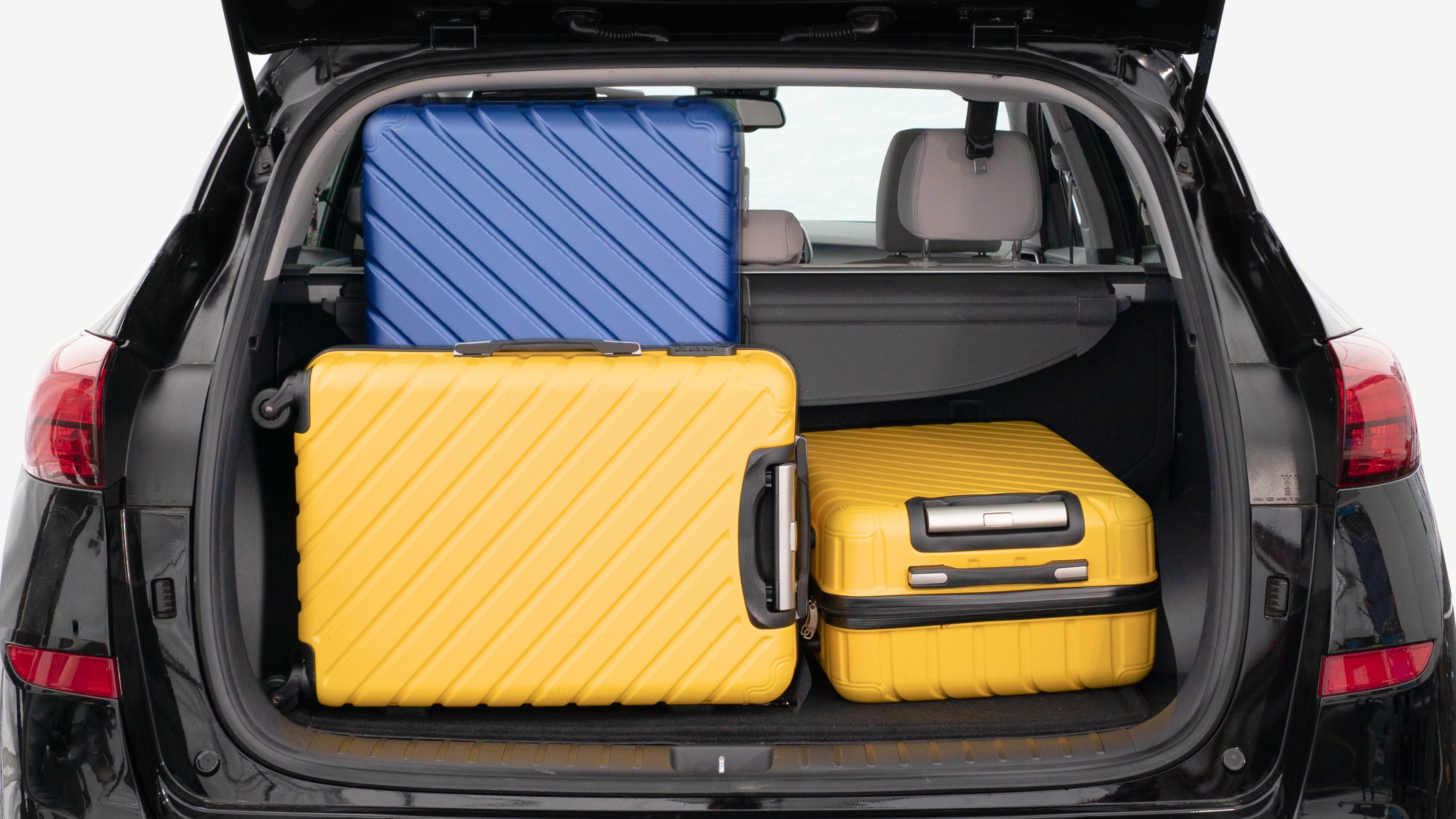 The trunk lid is open, showing a full view of the trunk space. Three large and two small suitcases are placed inside.