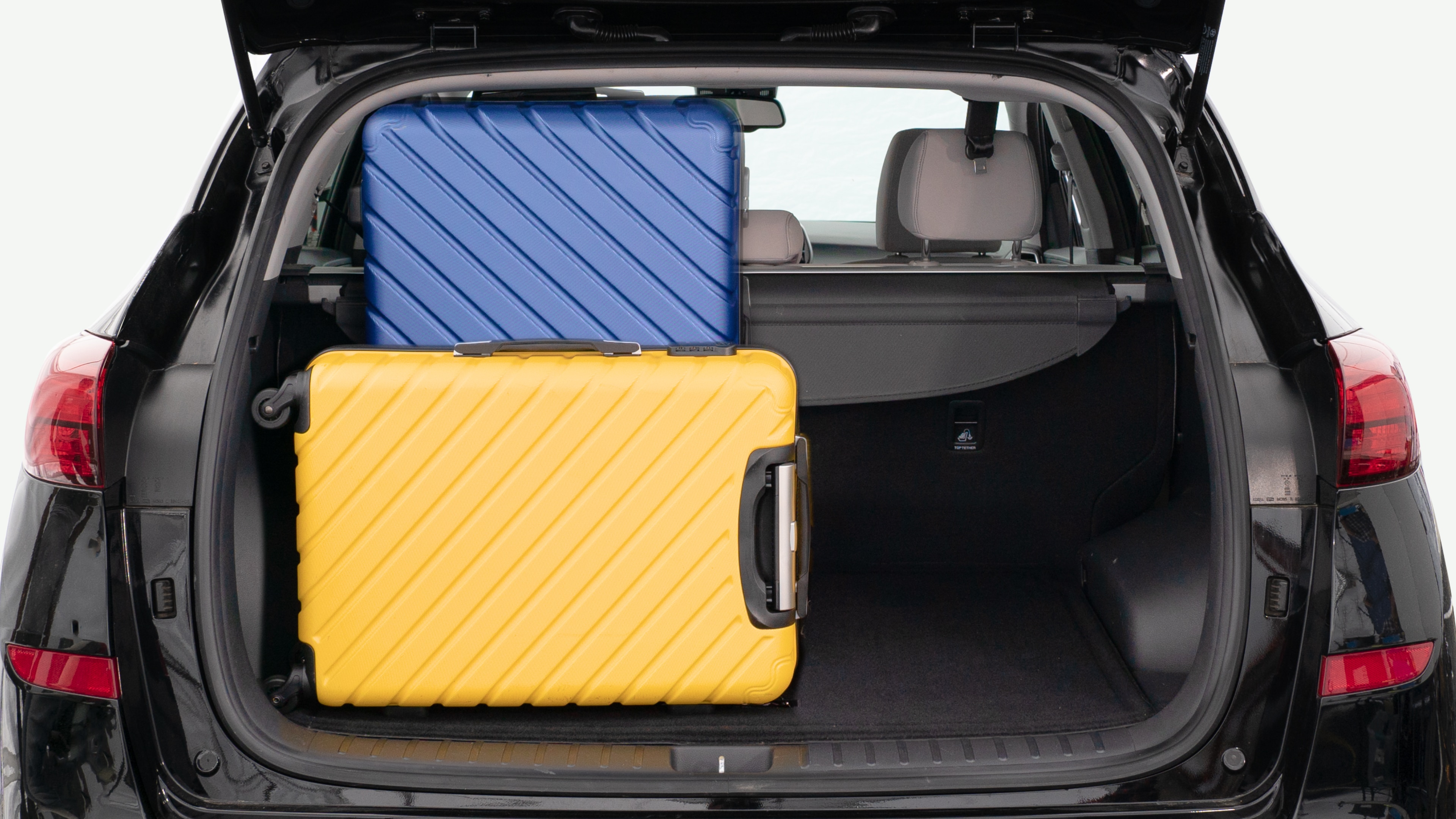 The trunk lid is open, showing a full view of the trunk space. Three large and two small suitcases are placed inside.