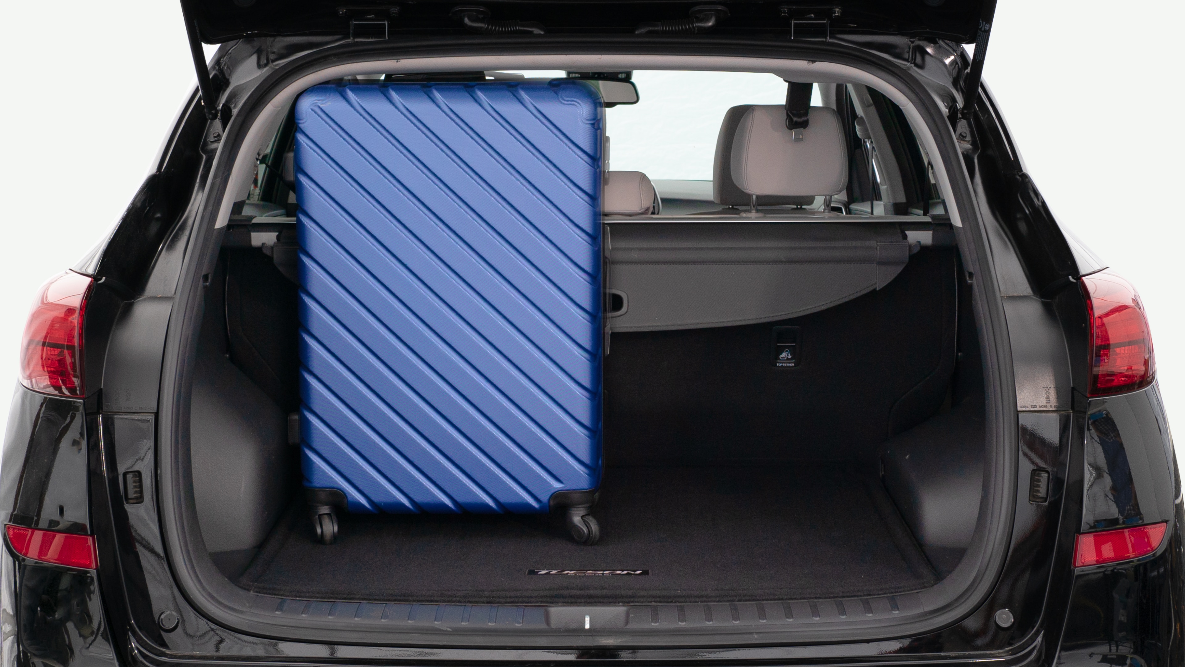 The trunk lid is open, showing a full view of the trunk space. Three large and two small suitcases are placed inside.