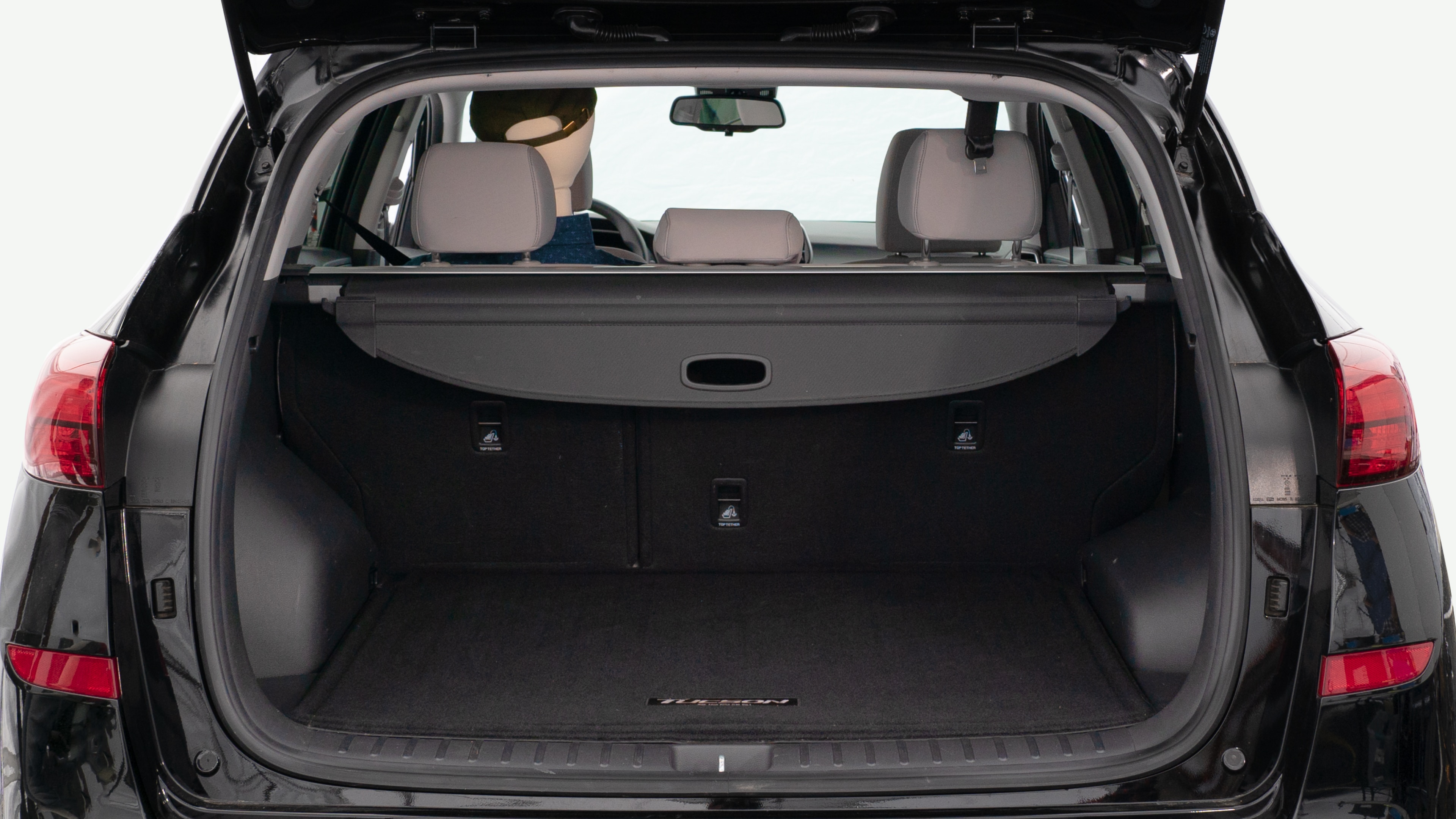 The trunk lid is open, showing a full view of the trunk space. Three large and two small suitcases are placed inside.
