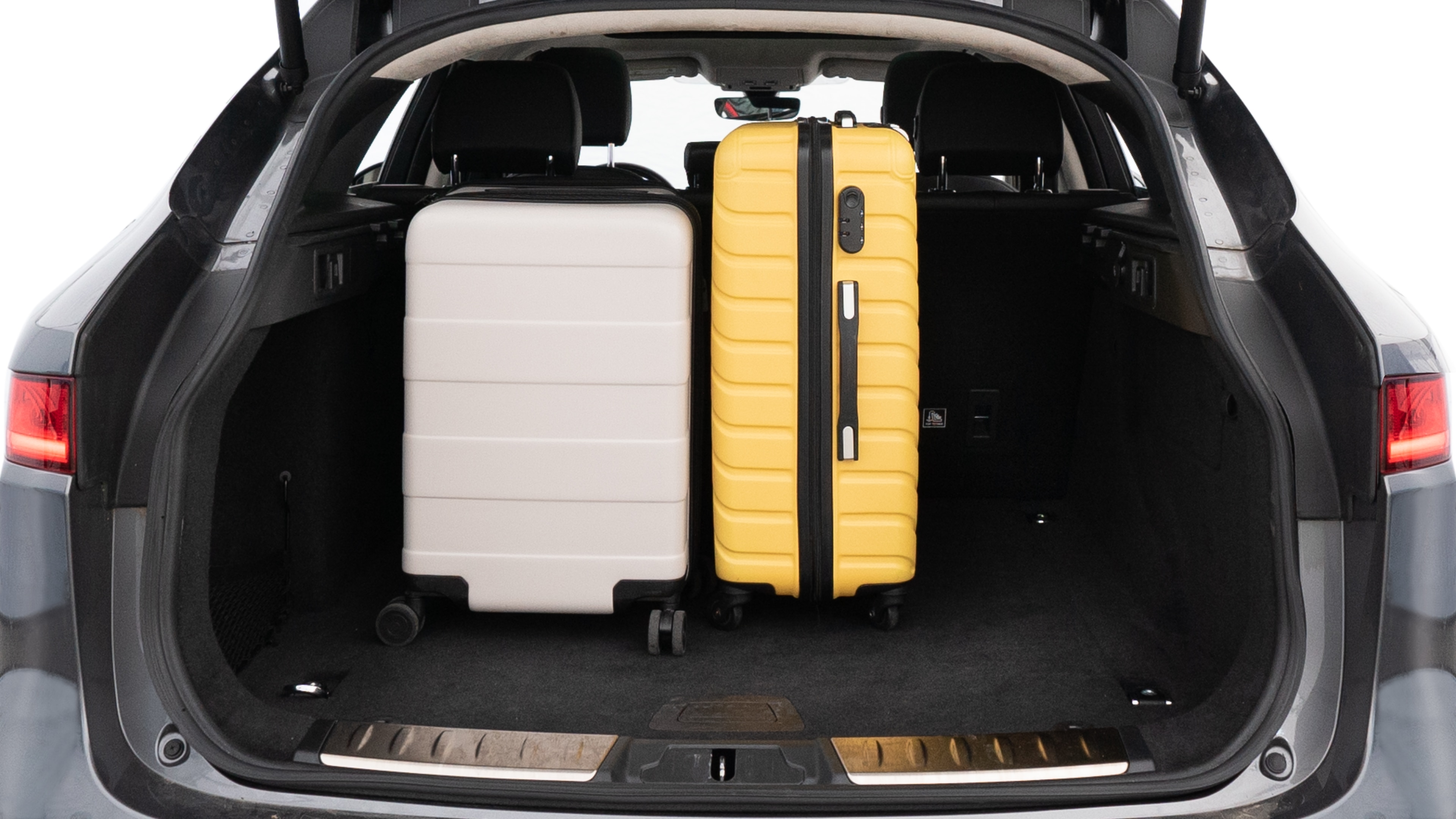 The trunk lid is open, showing full view of the trunk space. Two medium and two small suitcases are placed inside.