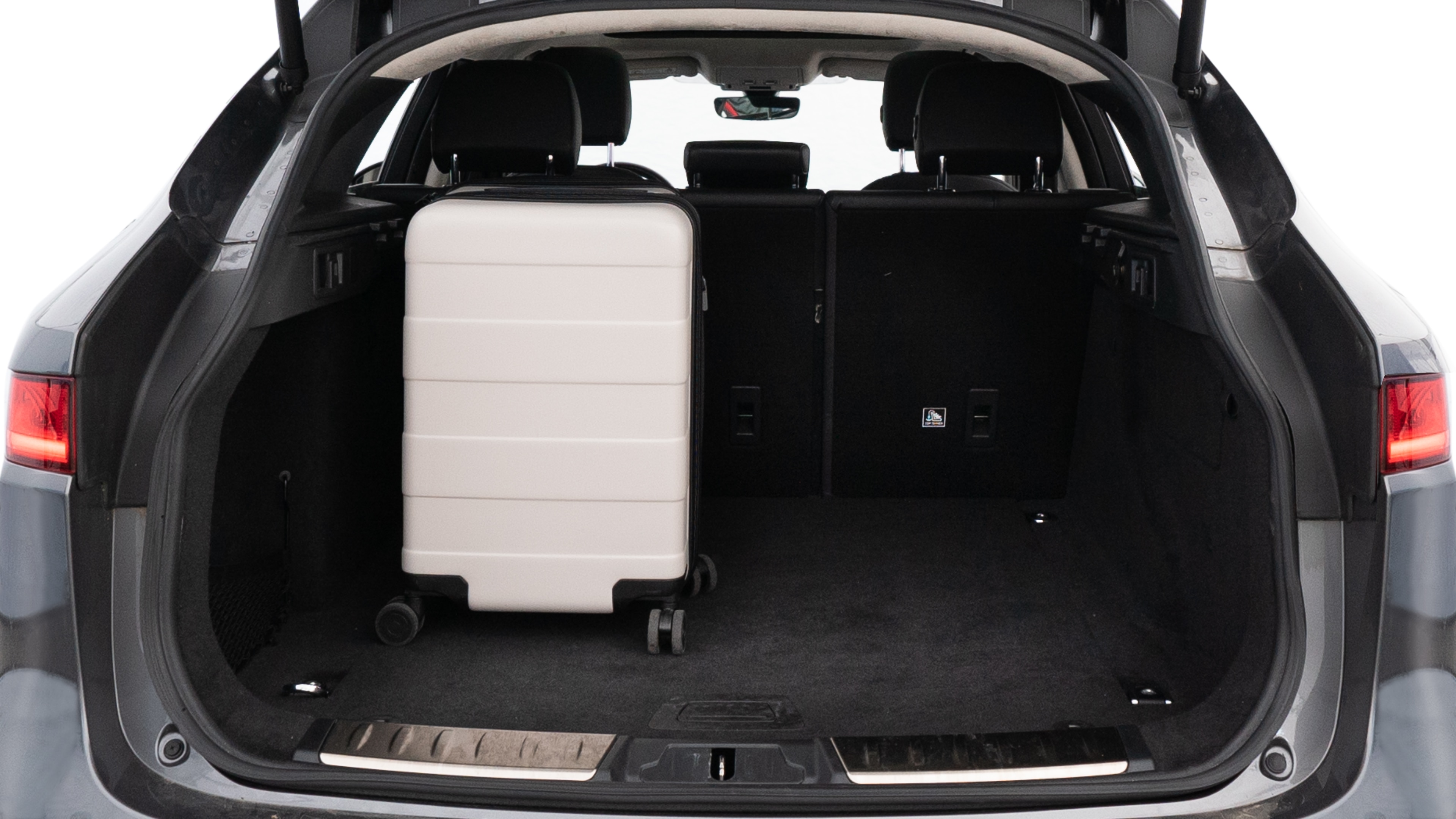 The trunk lid is open, showing full view of the trunk space. Two medium and two small suitcases are placed inside.