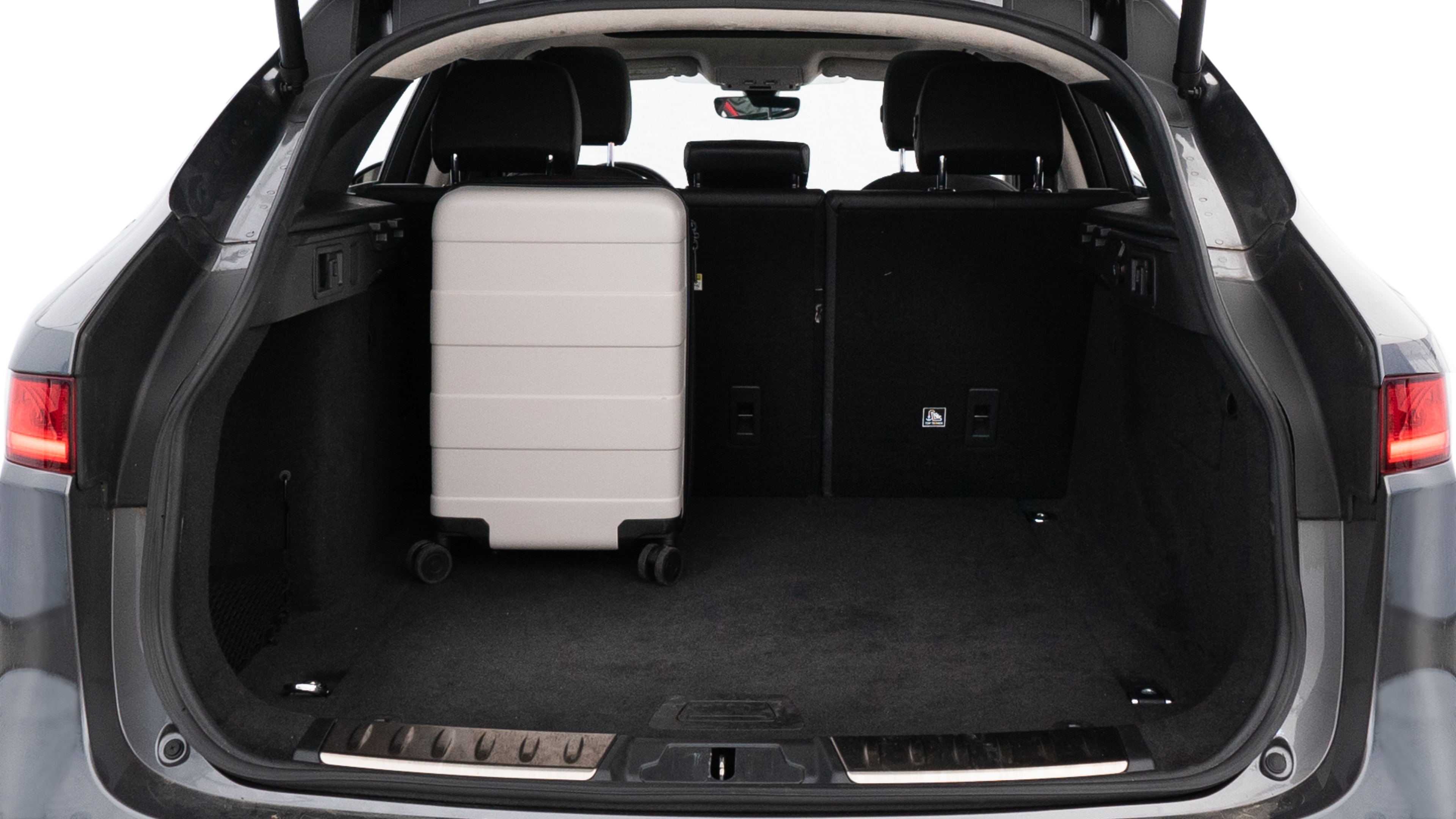 The trunk lid is open, showing full view of the trunk space. Two medium and two small suitcases are placed inside.