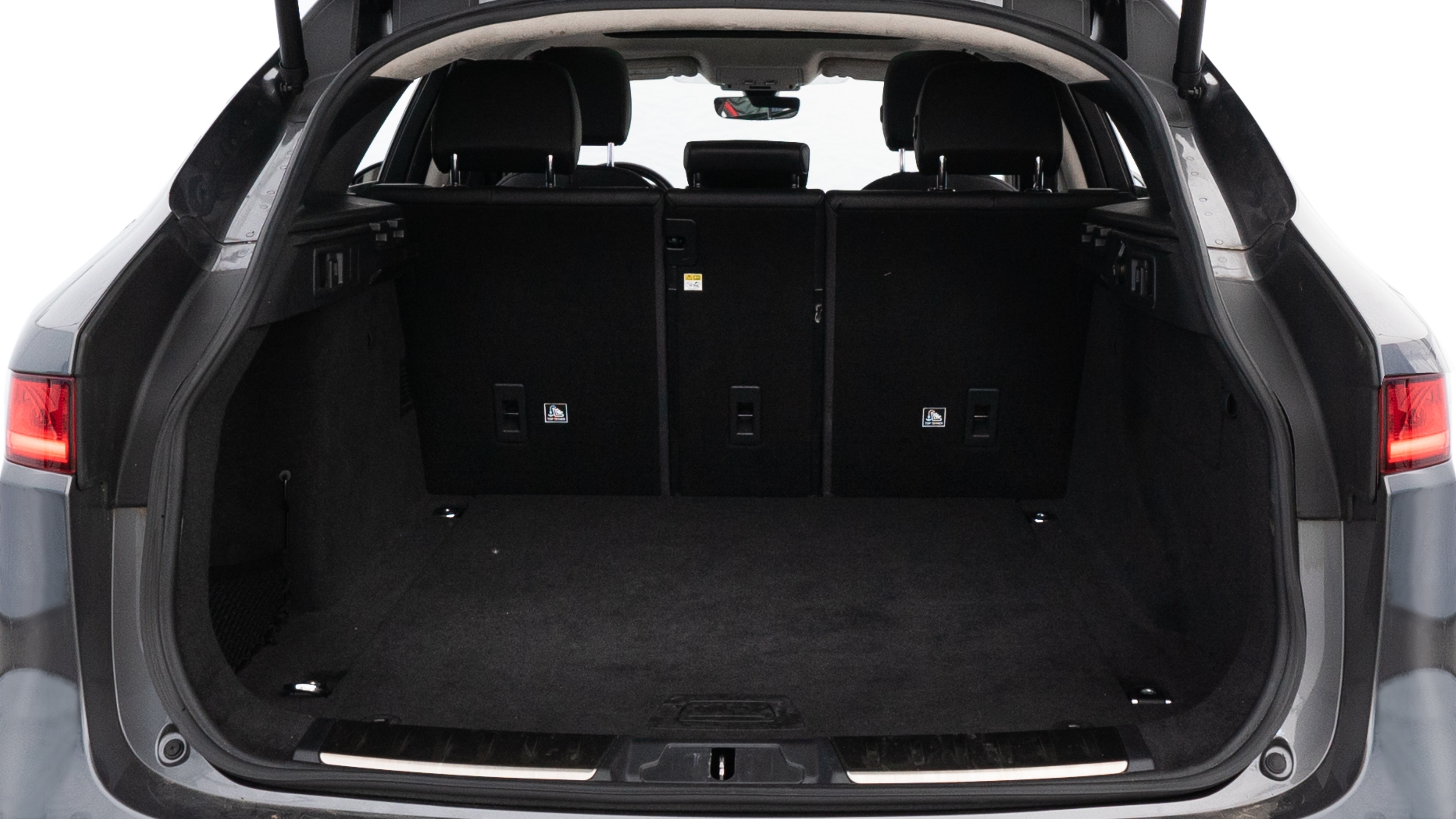 The trunk lid is open, showing full view of the trunk space. Two medium and two small suitcases are placed inside.
