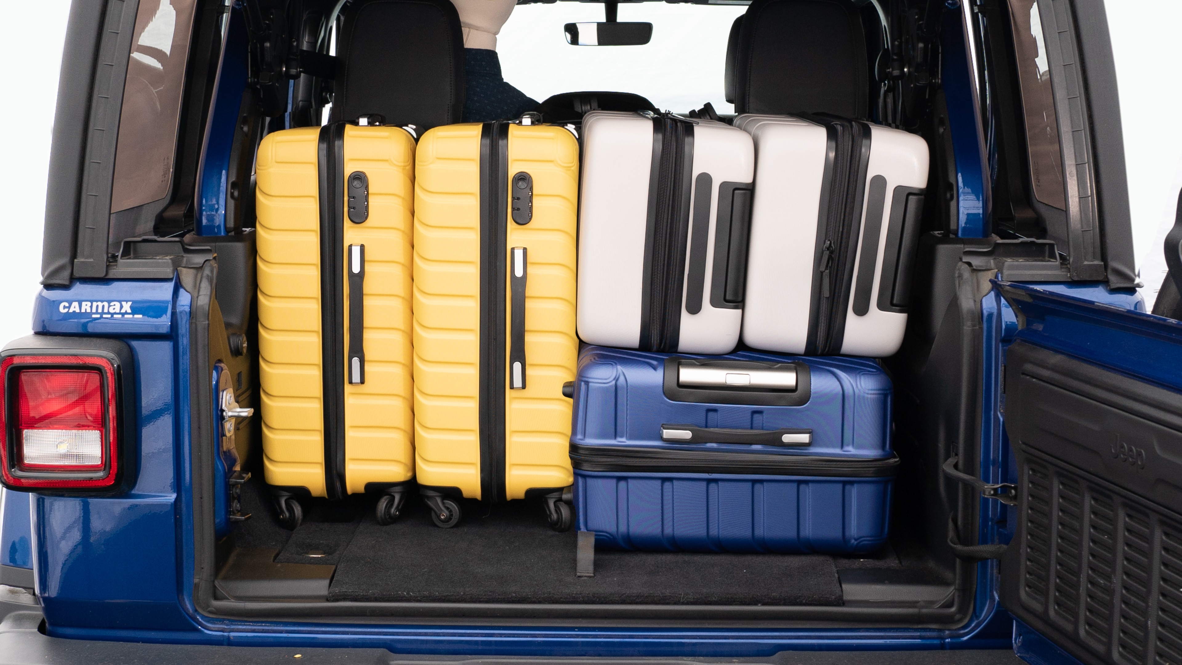 The trunk lid is open, showing a full view of the trunk space. Three large suitcases and two small suitcases placed inside.