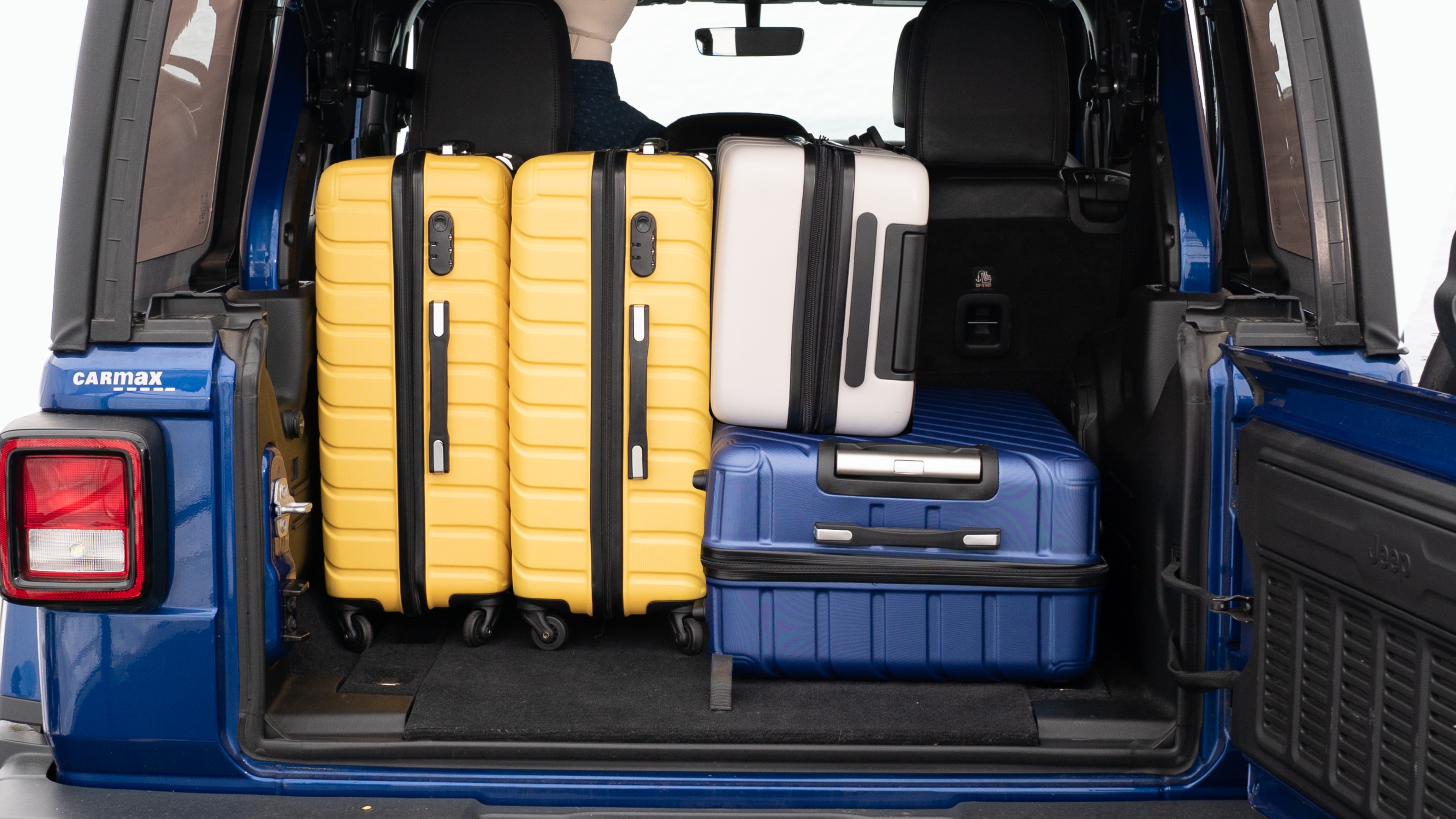 The trunk lid is open, showing a full view of the trunk space. Three large suitcases and two small suitcases placed inside.