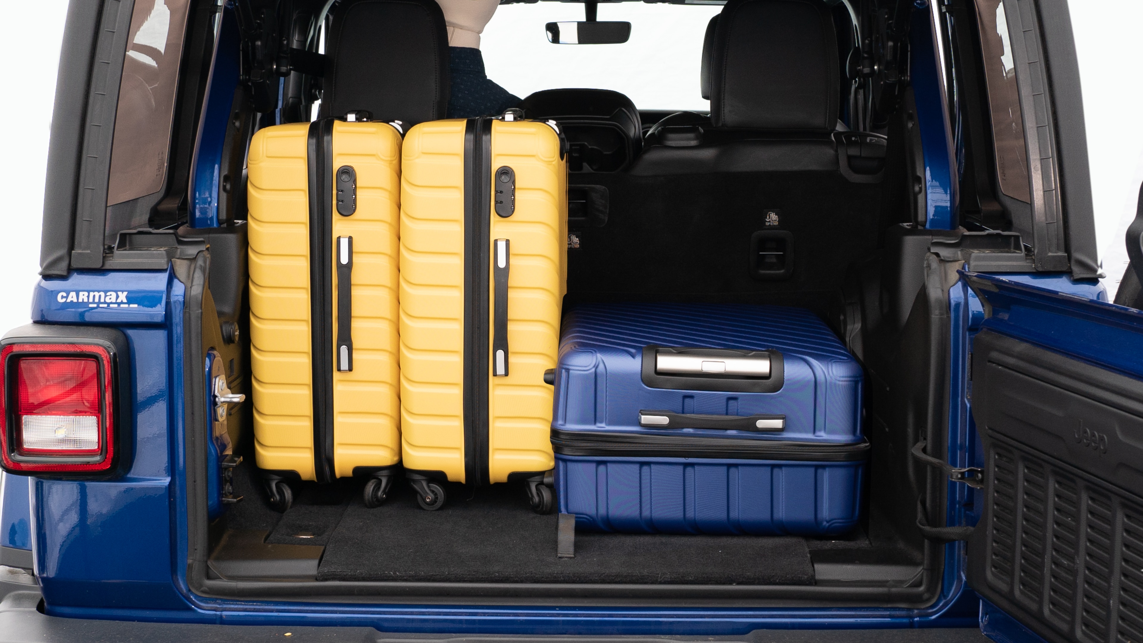 The trunk lid is open, showing a full view of the trunk space. Three large suitcases and two small suitcases placed inside.