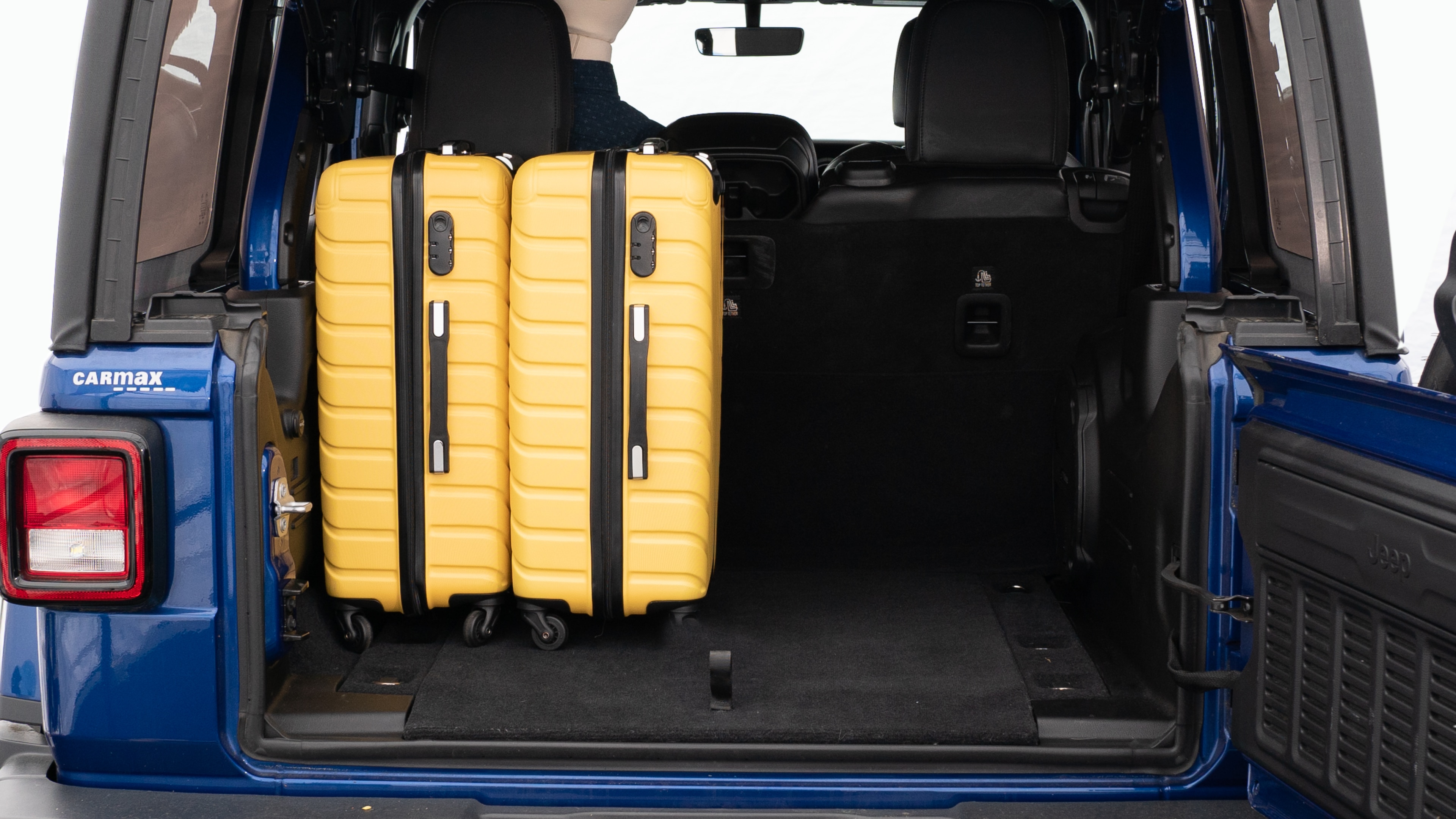 The trunk lid is open, showing a full view of the trunk space. Three large suitcases and two small suitcases placed inside.