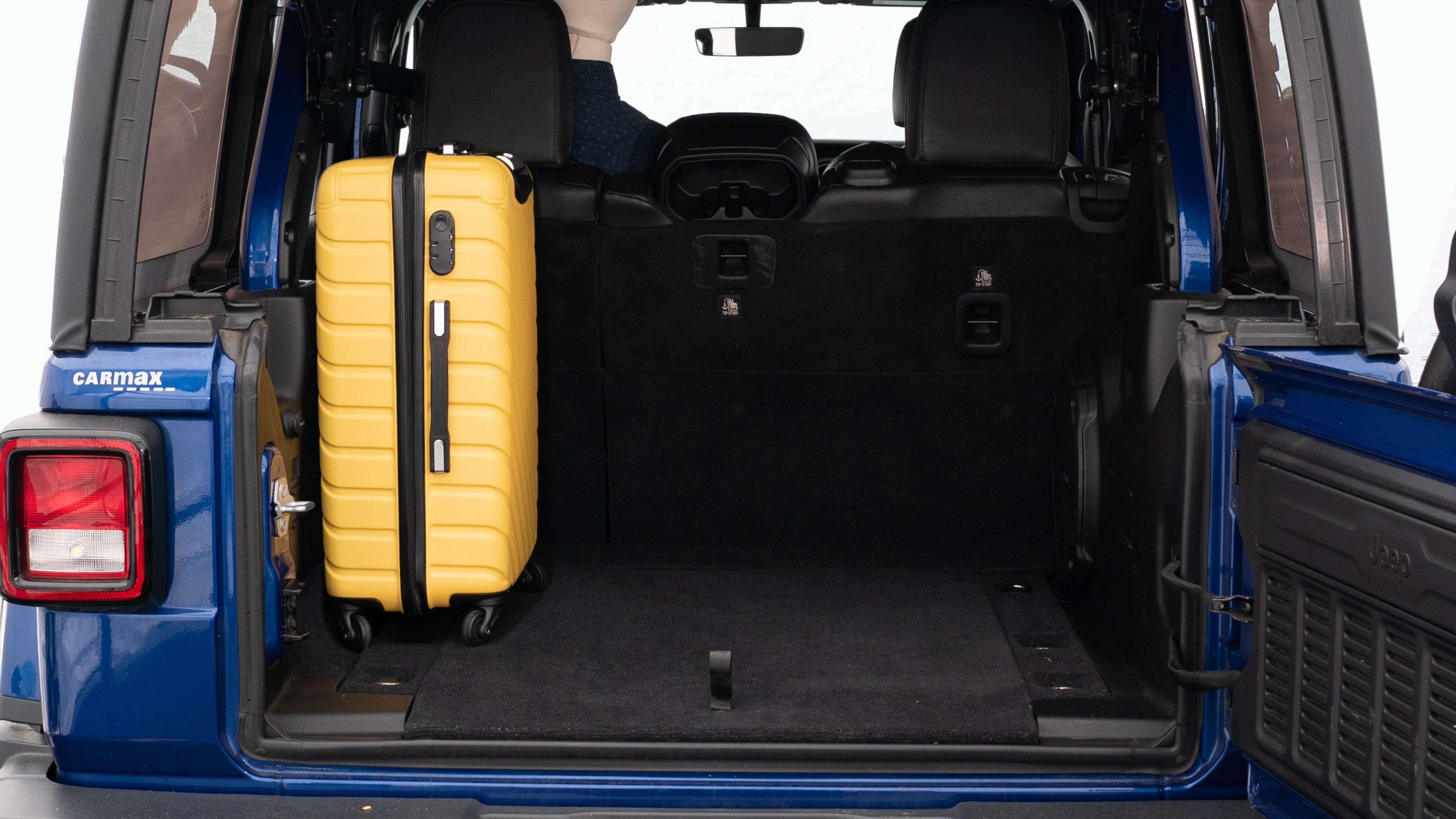 The trunk lid is open, showing a full view of the trunk space. Three large suitcases and two small suitcases placed inside.