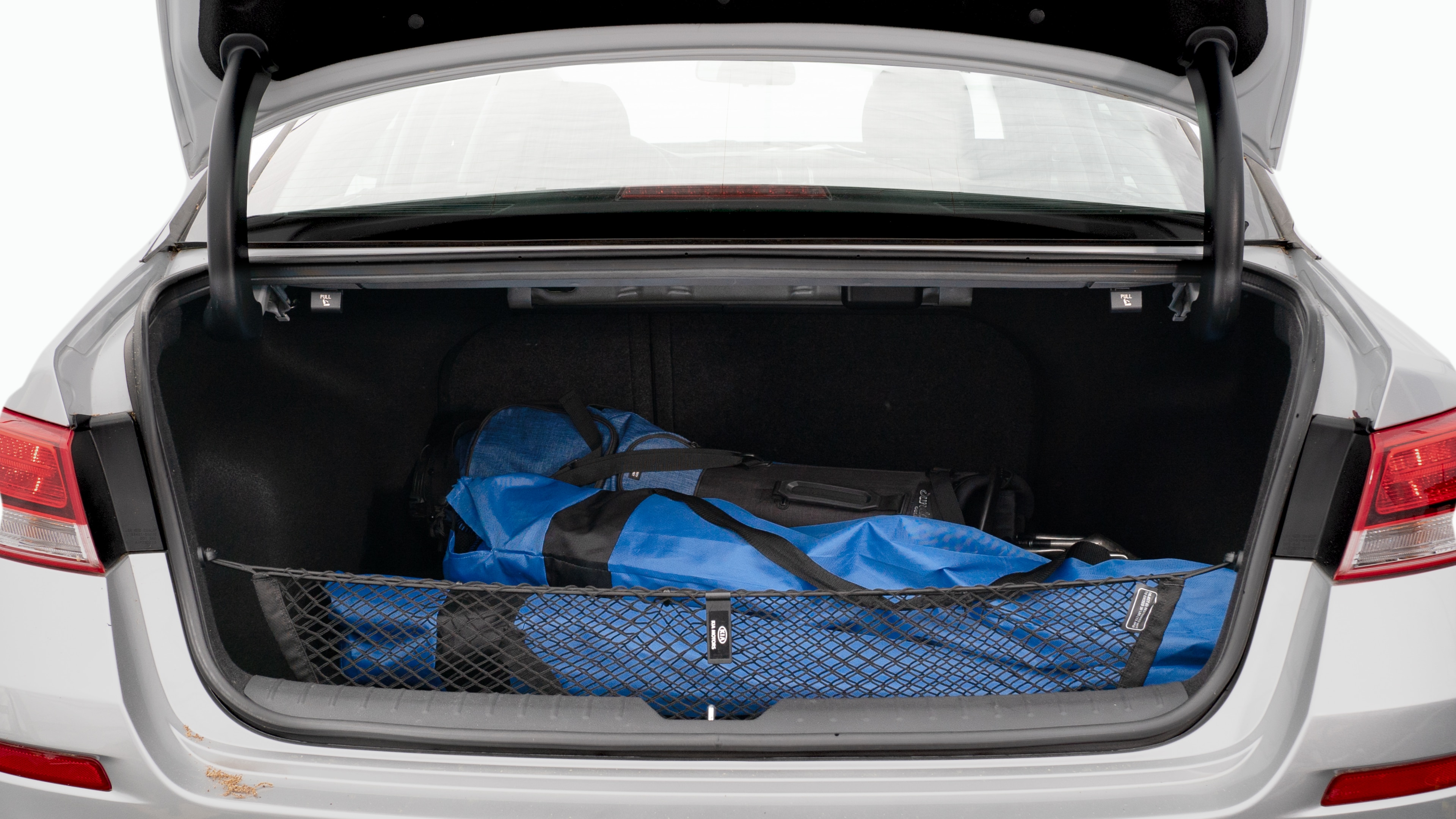 The trunk lid is open showing full view of the trunk. A baby stroller, three grocery carriers, two camping chairs in the carrying bag, and a set of golf clubs are placed inside.