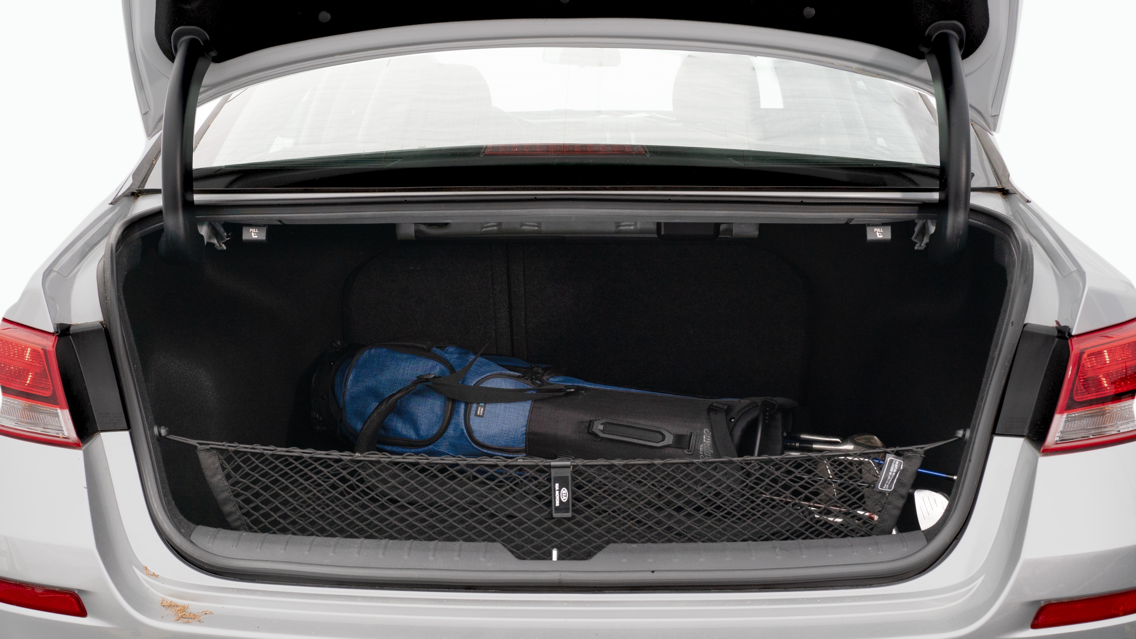 The trunk lid is open showing full view of the trunk. A baby stroller, three grocery carriers, two camping chairs in the carrying bag, and a set of golf clubs are placed inside.