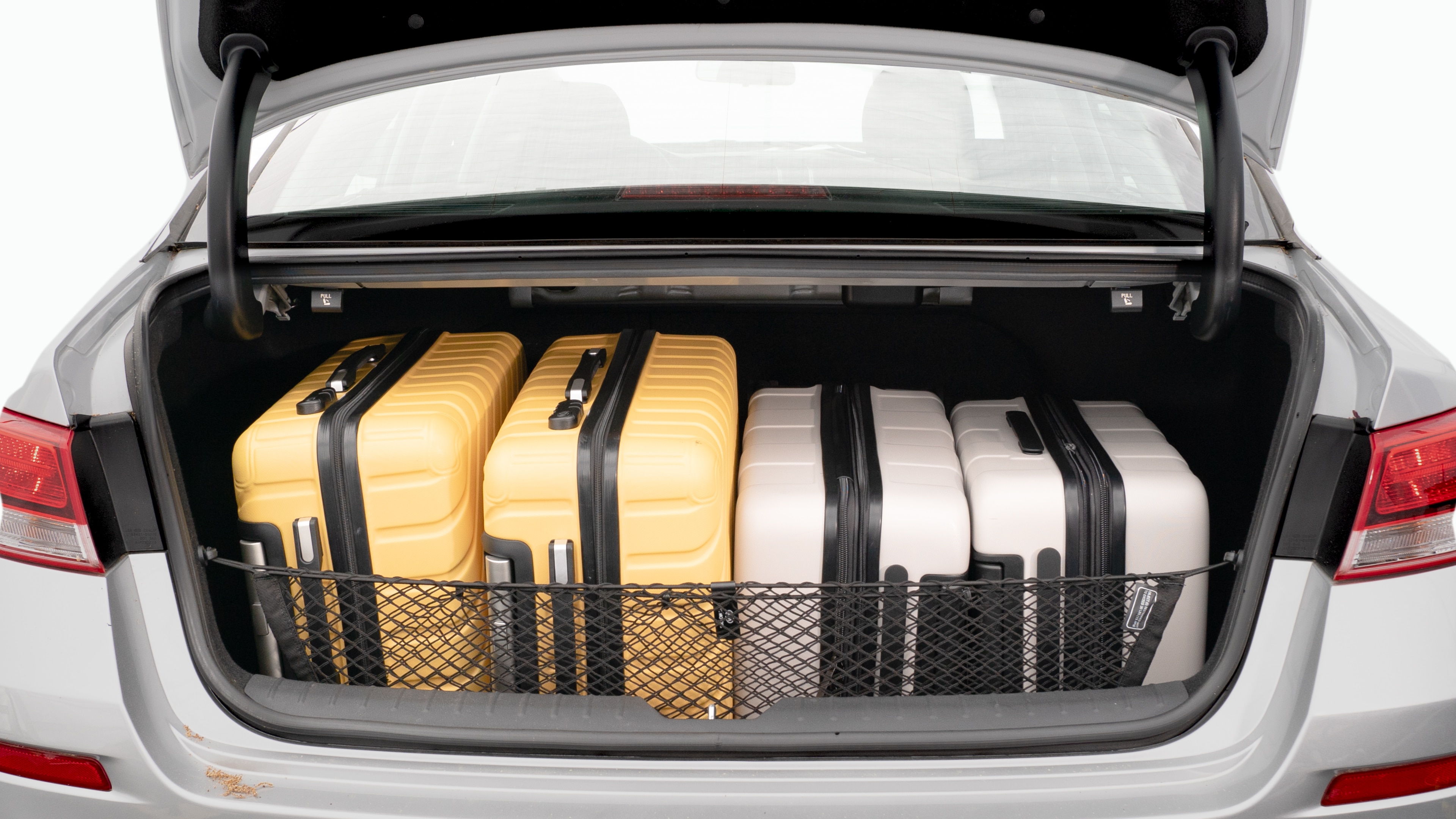 The trunk lid is open, showing a full view of the trunk space. Two large and two small suitcases are placed on there side.