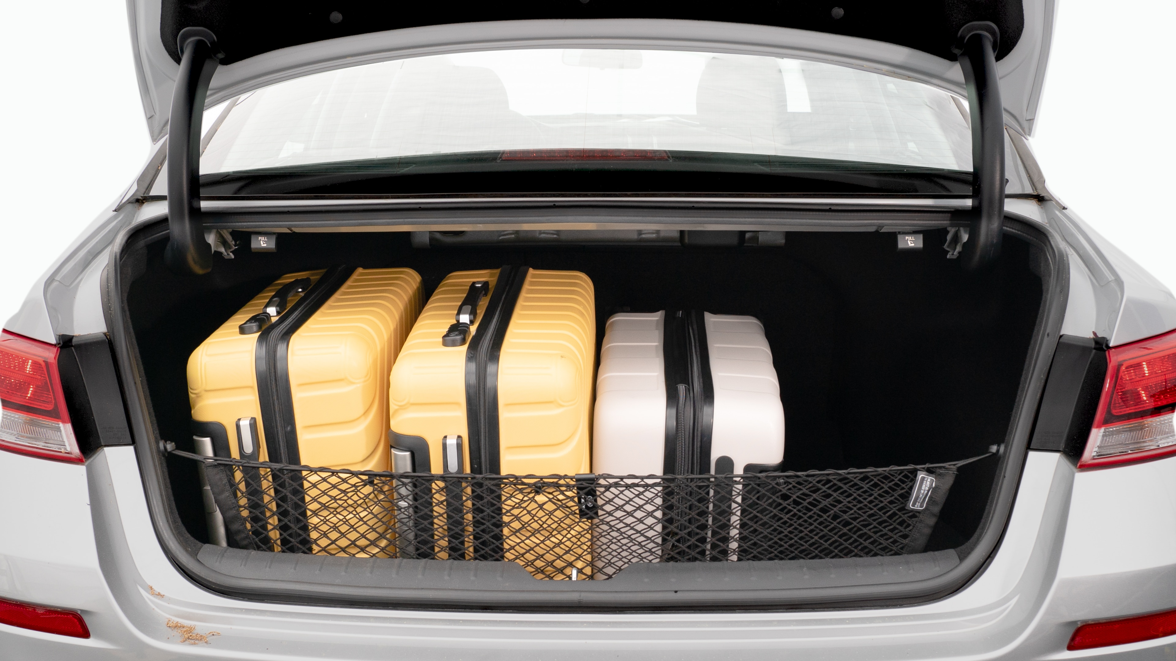 The trunk lid is open, showing a full view of the trunk space. Two large and two small suitcases are placed on there side.