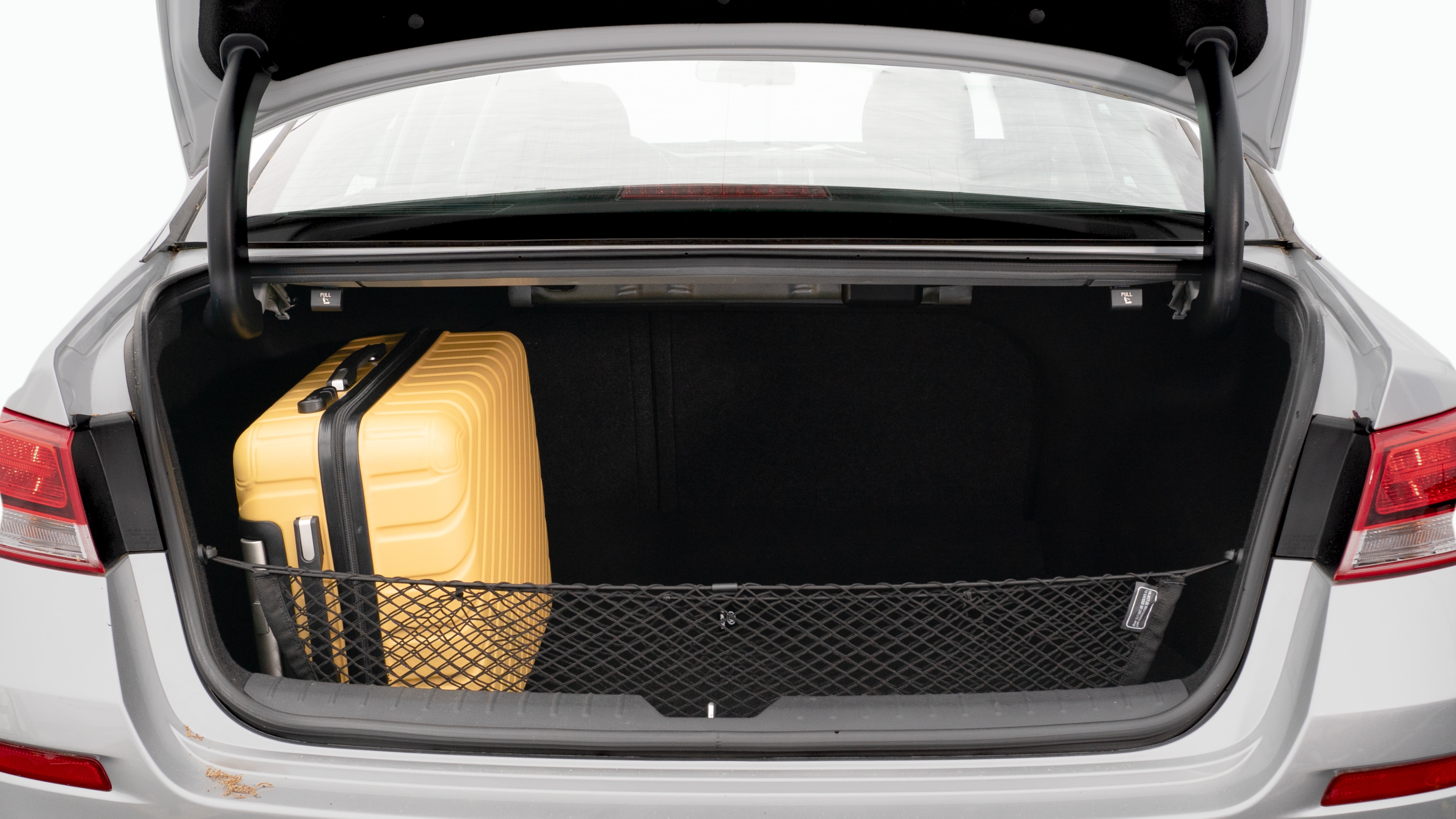 The trunk lid is open, showing a full view of the trunk space. Two large and two small suitcases are placed on there side.