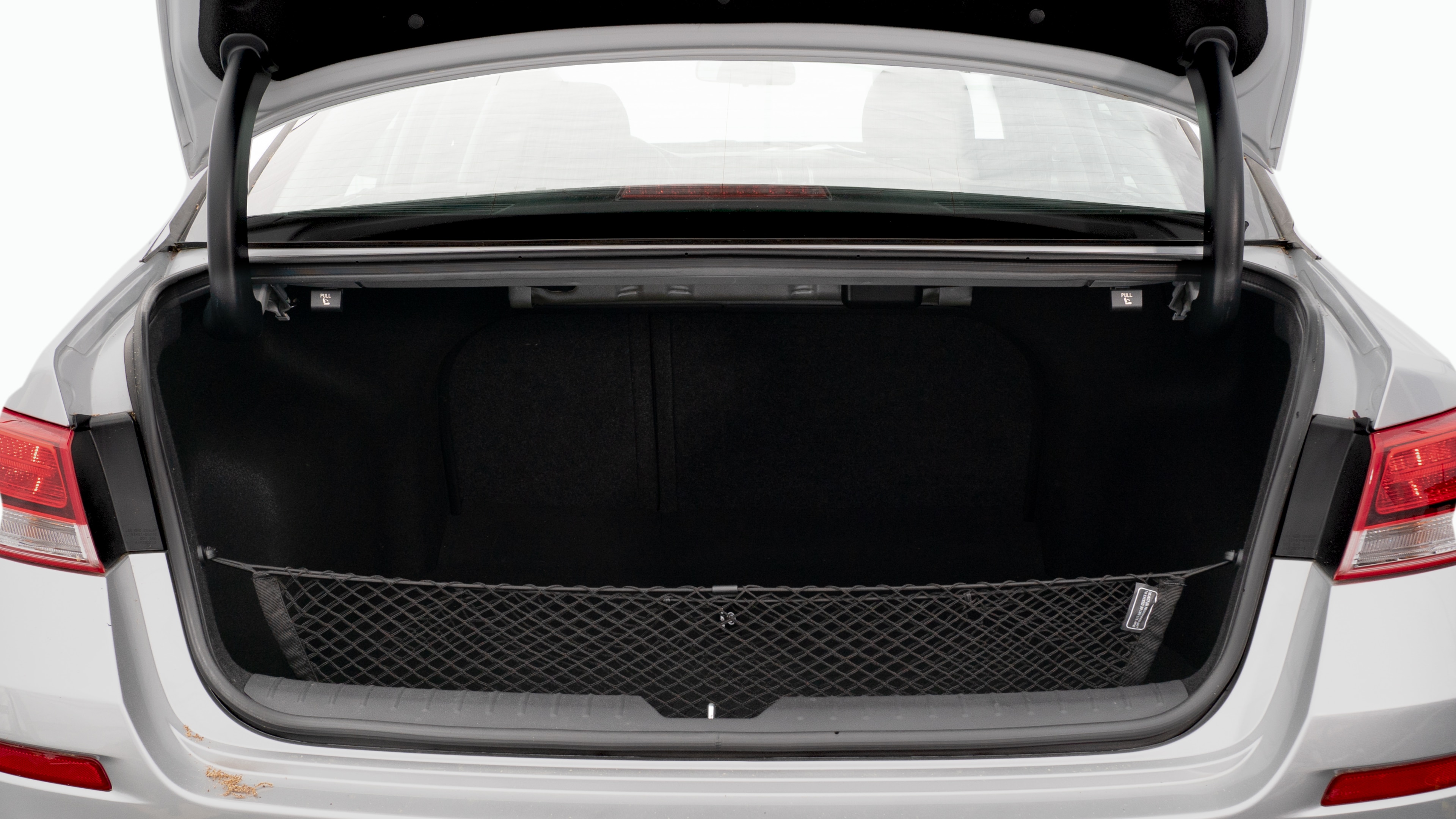 The trunk lid is open, showing a full view of the trunk space. Two large and two small suitcases are placed on there side.