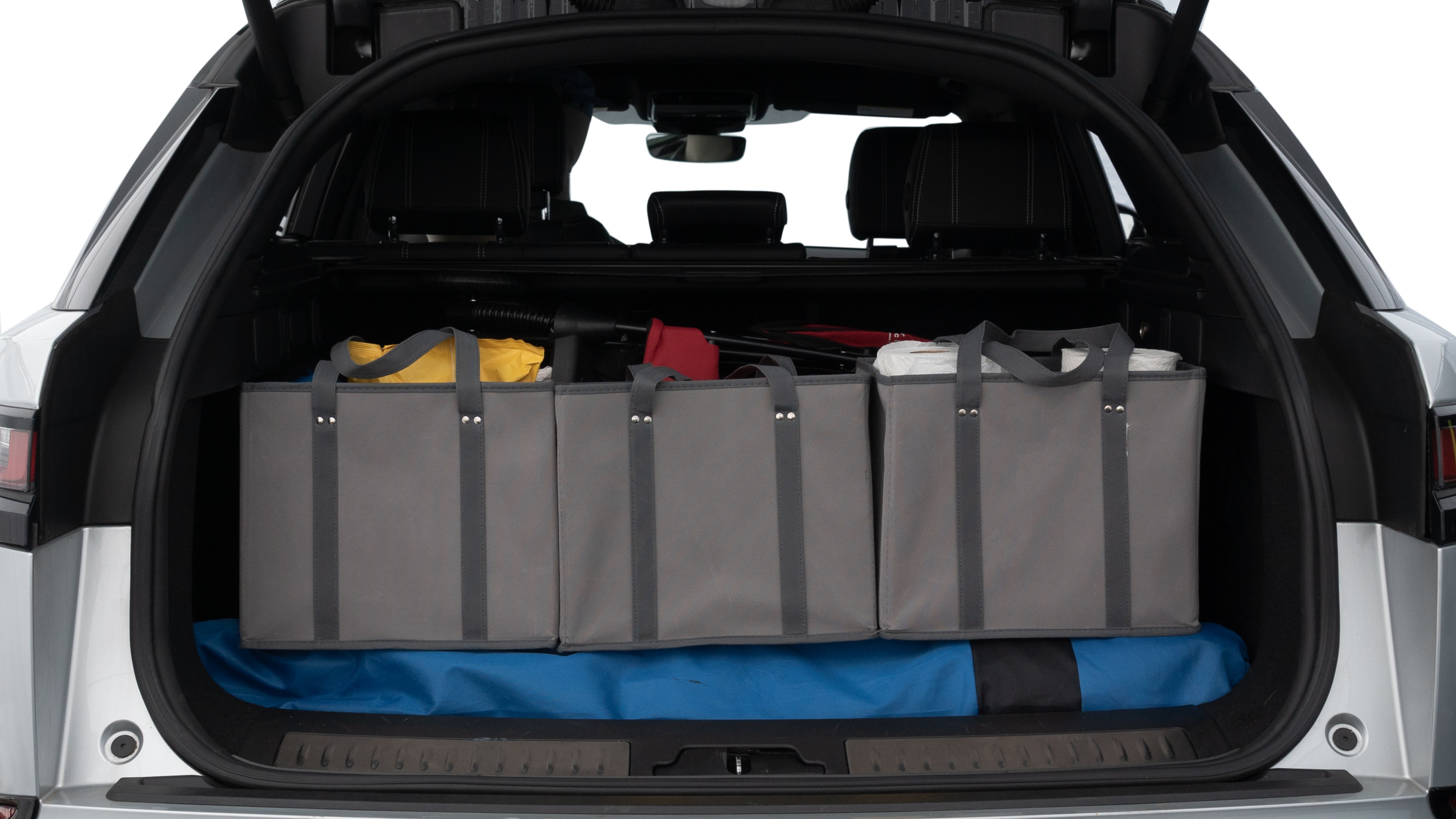 The trunk lid is open showing full view of the trunk. A baby stroller, three grocery carriers, two camping chairs in the carrying bag, and a set of golf clubs are placed inside.