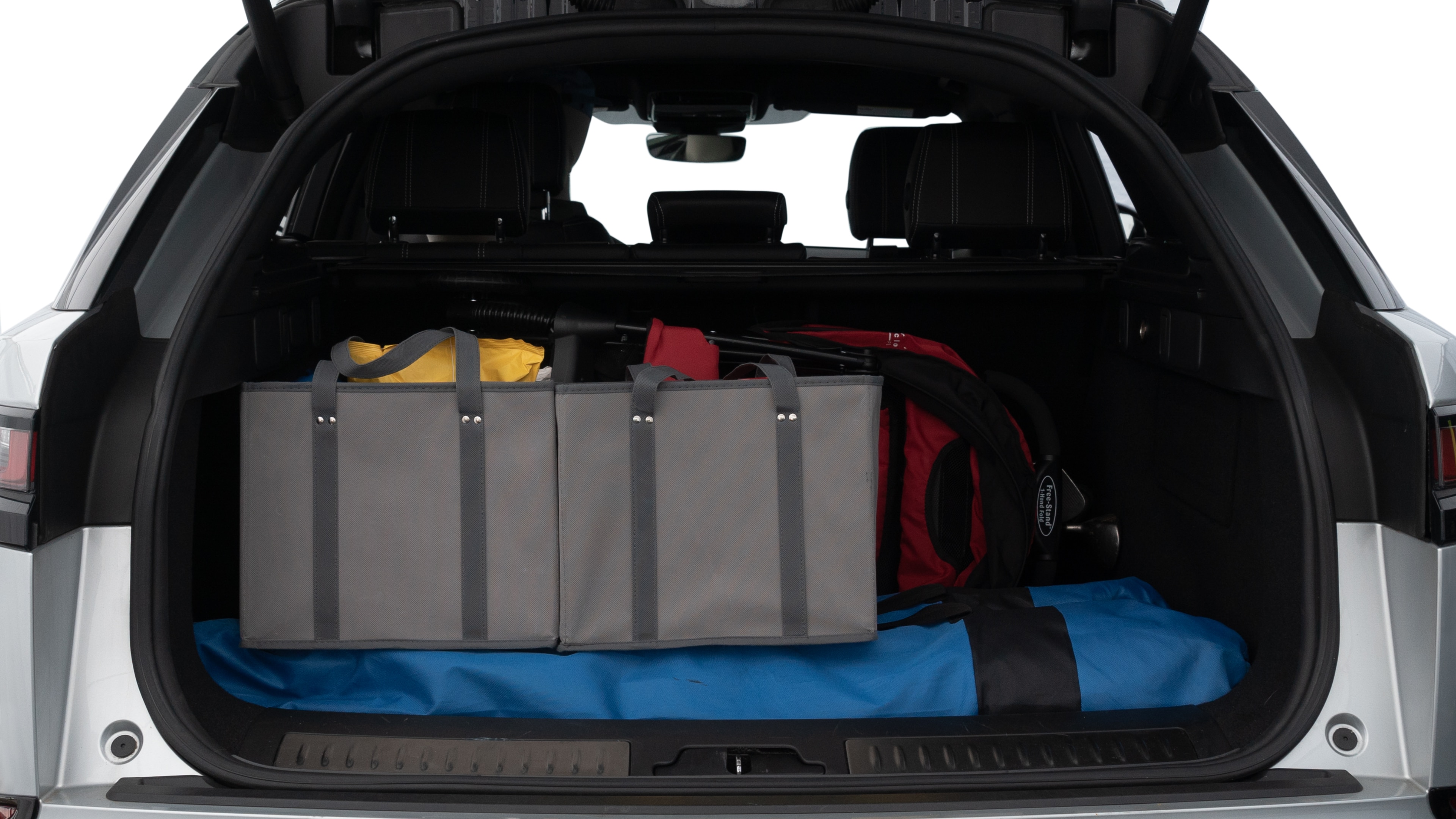 The trunk lid is open showing full view of the trunk. A baby stroller, three grocery carriers, two camping chairs in the carrying bag, and a set of golf clubs are placed inside.