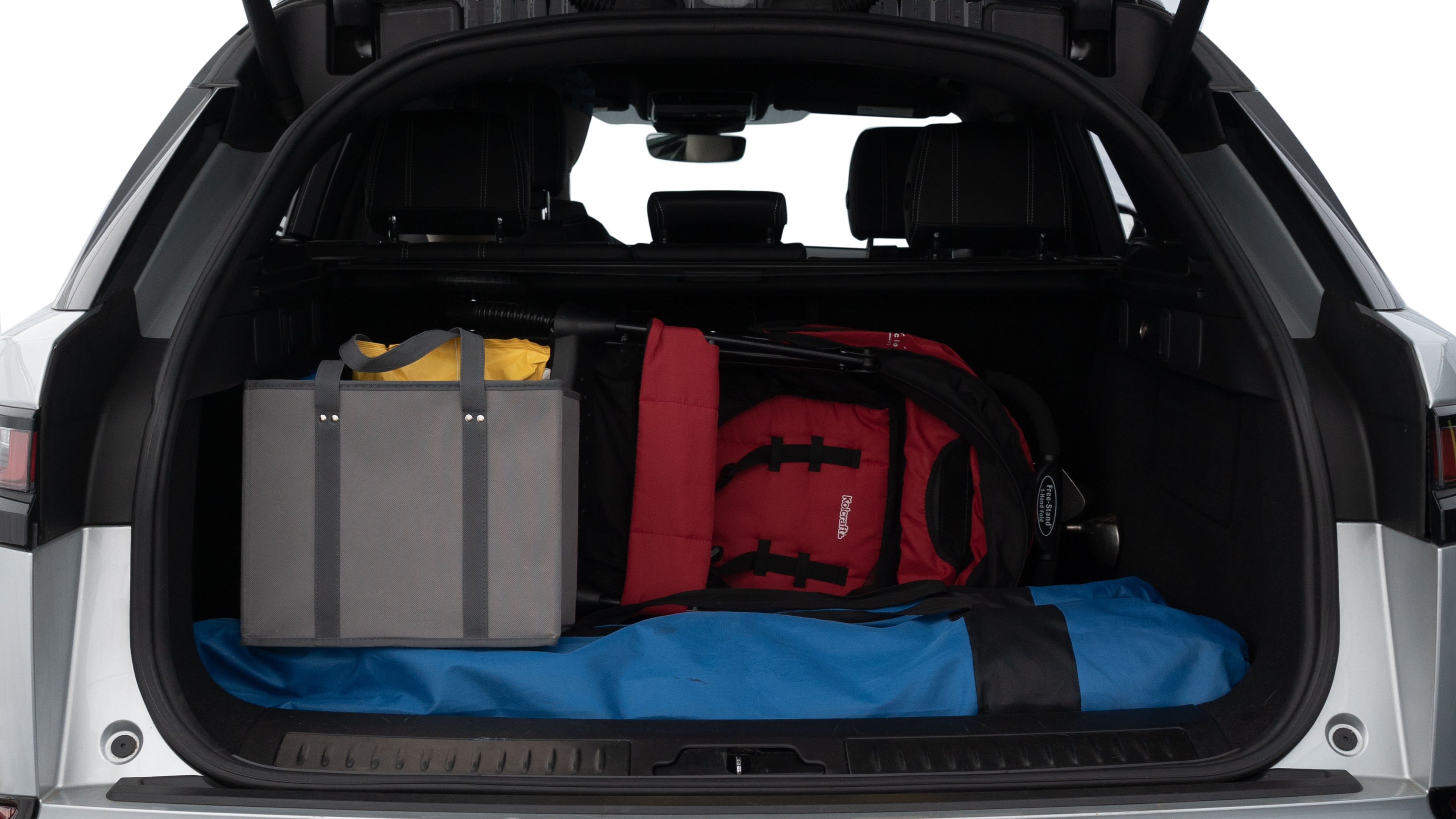 The trunk lid is open showing full view of the trunk. A baby stroller, three grocery carriers, two camping chairs in the carrying bag, and a set of golf clubs are placed inside.