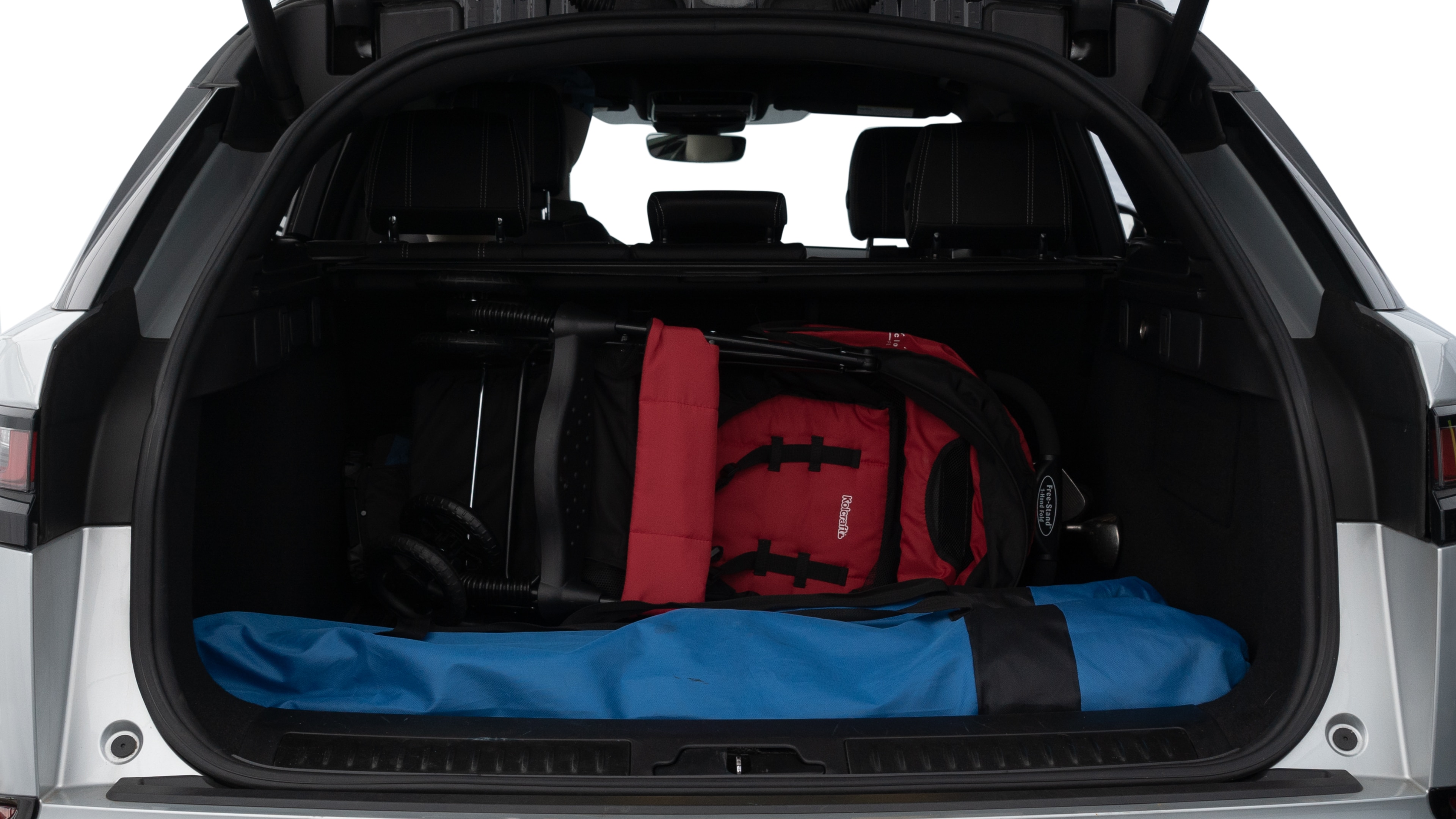 The trunk lid is open showing full view of the trunk. A baby stroller, three grocery carriers, two camping chairs in the carrying bag, and a set of golf clubs are placed inside.