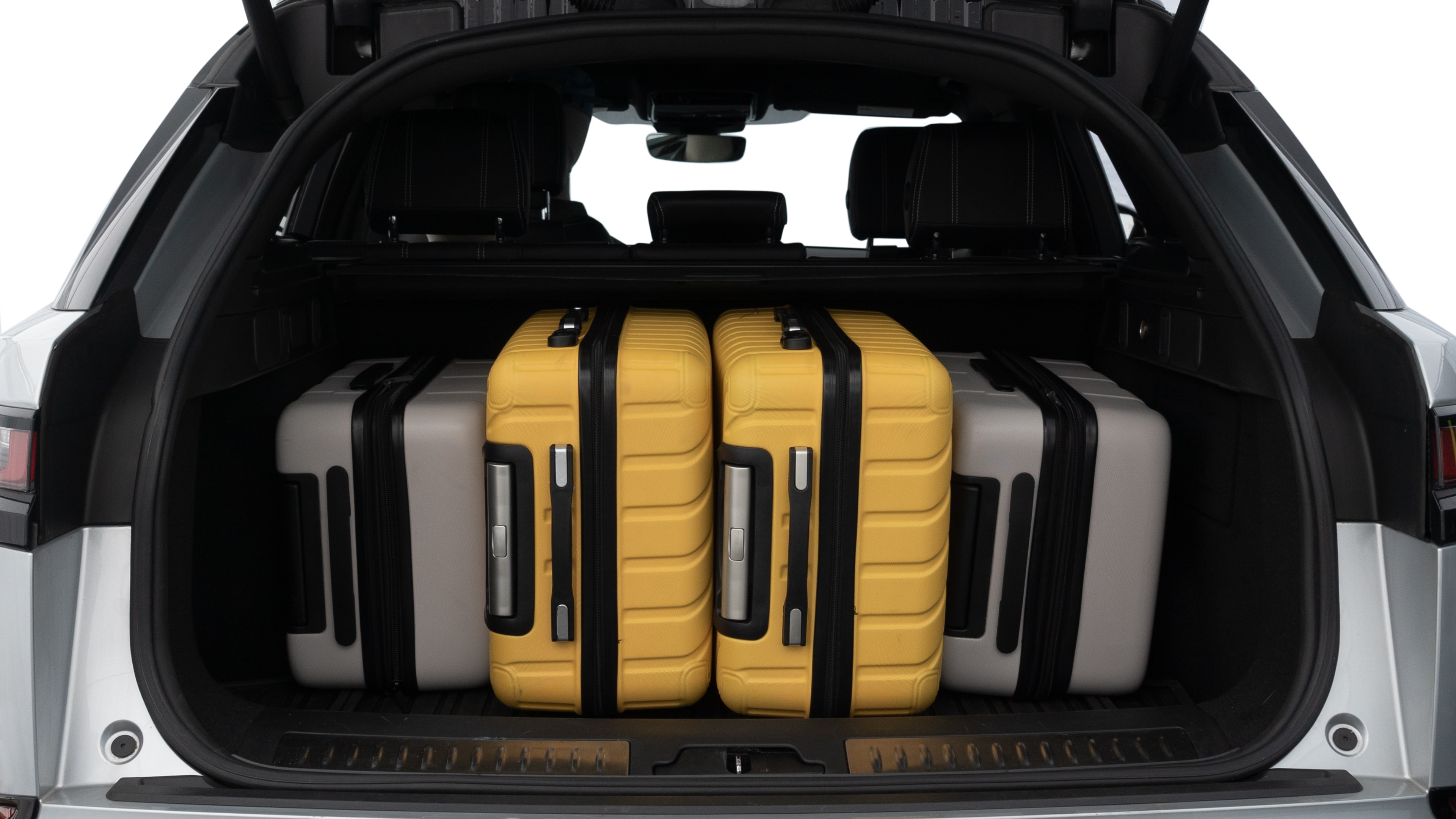 The trunk lid is open, showing full view of the trunk space. Two medium and two small suitcases are placed inside.