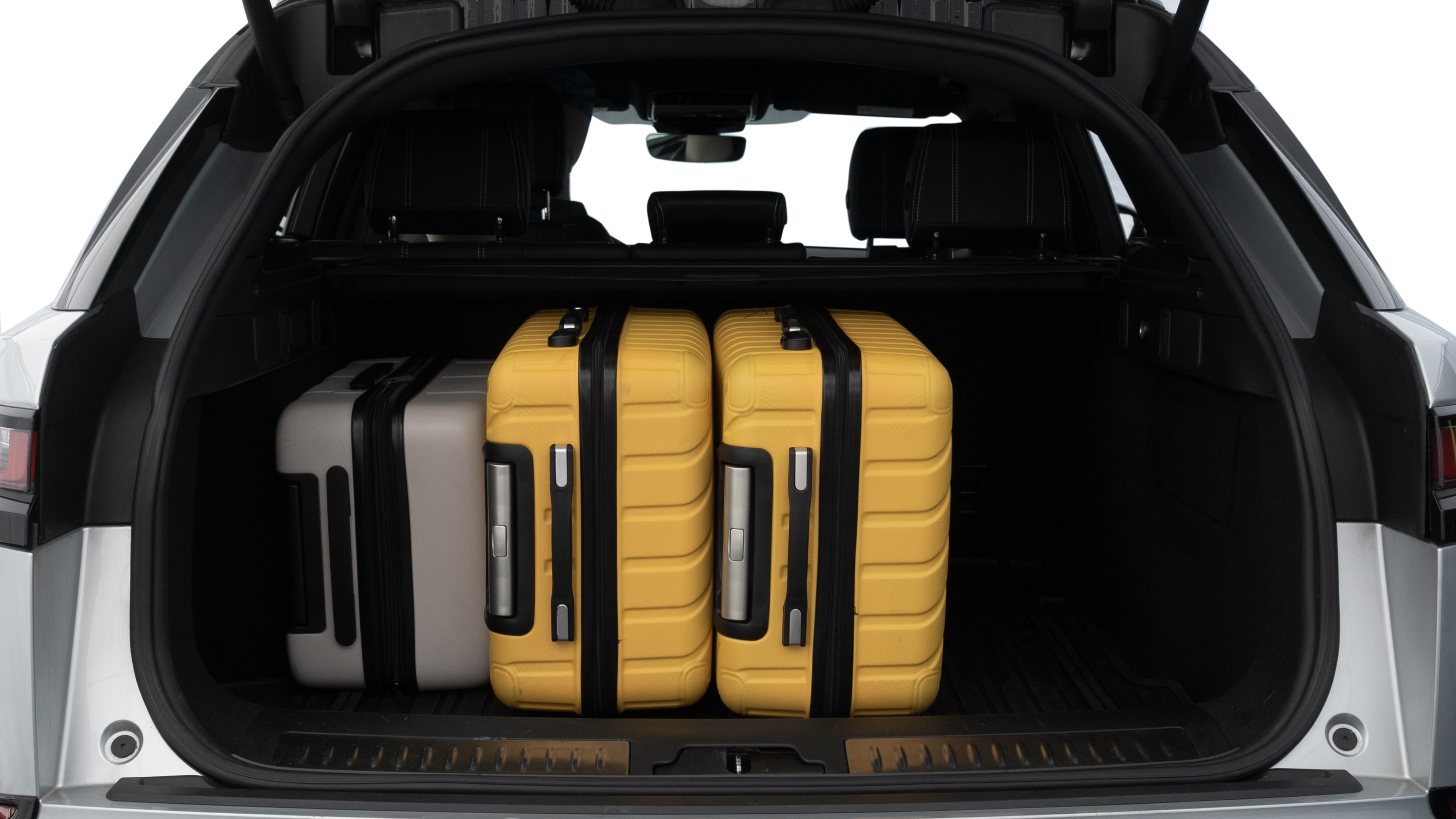 The trunk lid is open, showing full view of the trunk space. Two medium and two small suitcases are placed inside.